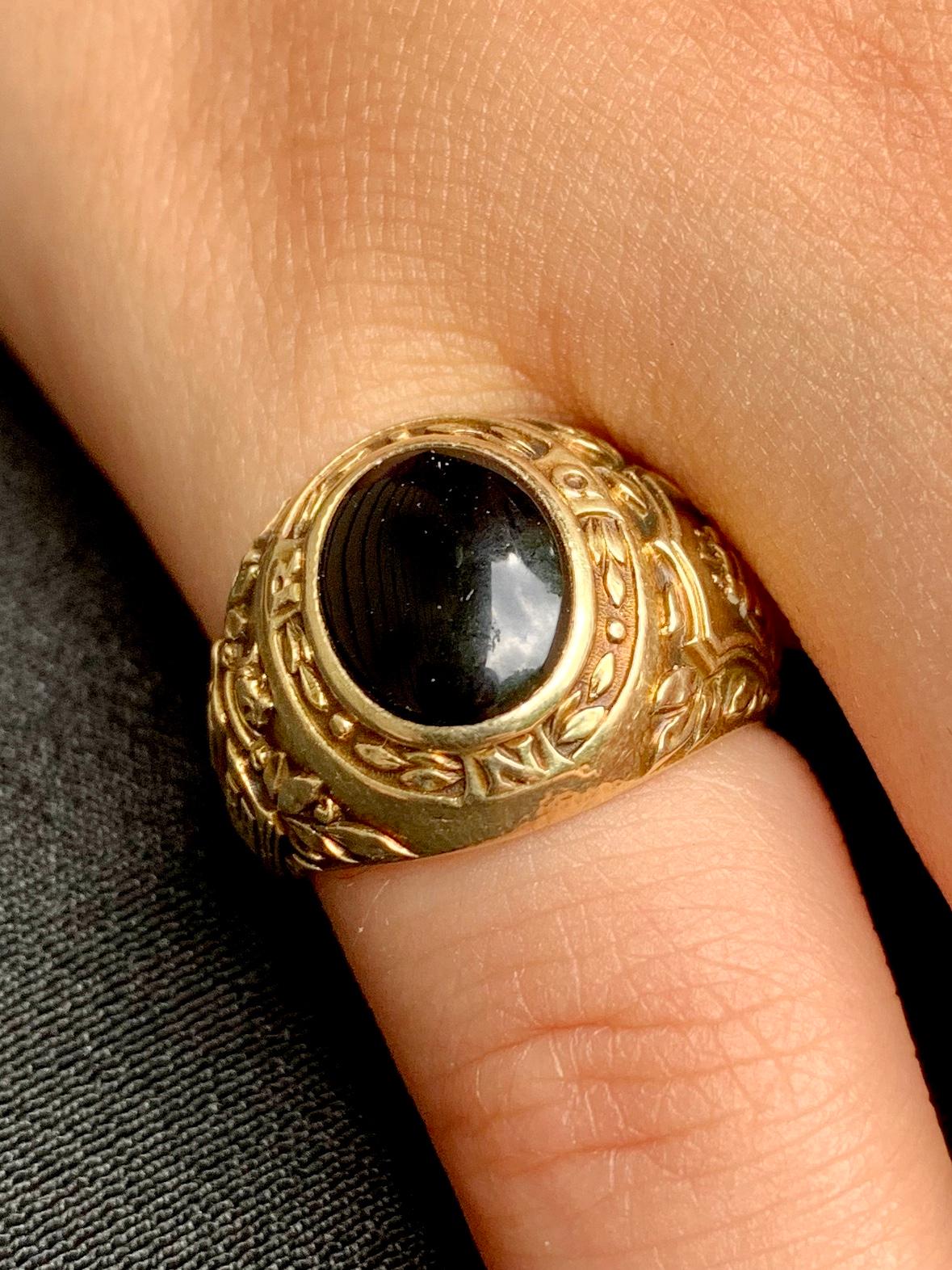  Vintage Tiffany & Co. 14K gold and cabochon onyx signet ring. Elaborately decorated with a three mast ship within a heraldic crest surrounded by laurel leaves on one side and a large open book with the date 1938 resting upon two crossed laurel