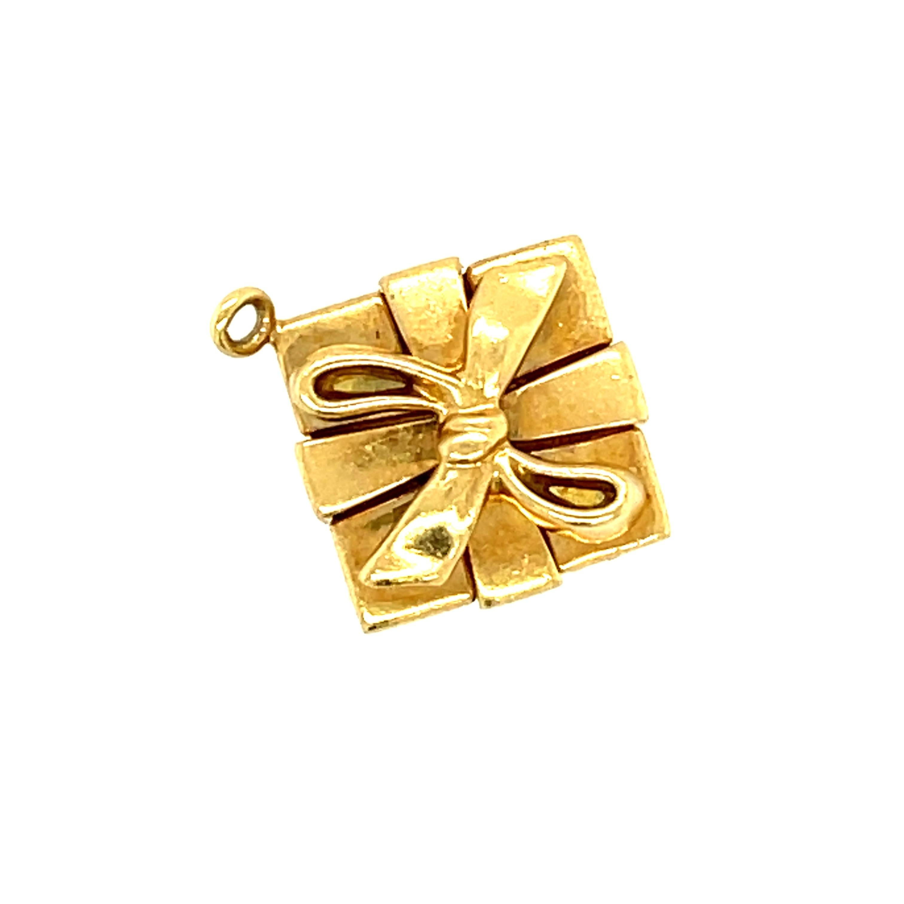 A vintage closed box with bow present charm made in 18k gold by Tiffany & Co. circa 2000. This charm is a rendering of the classic Tiffany blue box with a white bow made in 18k yellow gold. It is stamped Tiffany & Co. 750 on the bottom of the box.