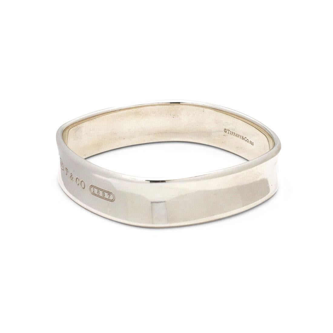 Authentic Tiffany & Co. Bracelet crafted in sterling silver. The bracelet is slightly square in shape and measures 14mm wide. The bracelet is stamped 925 and signed Tiffany & Co. on the inside. The bracelet highlights a 925 stamp, T & CO signature