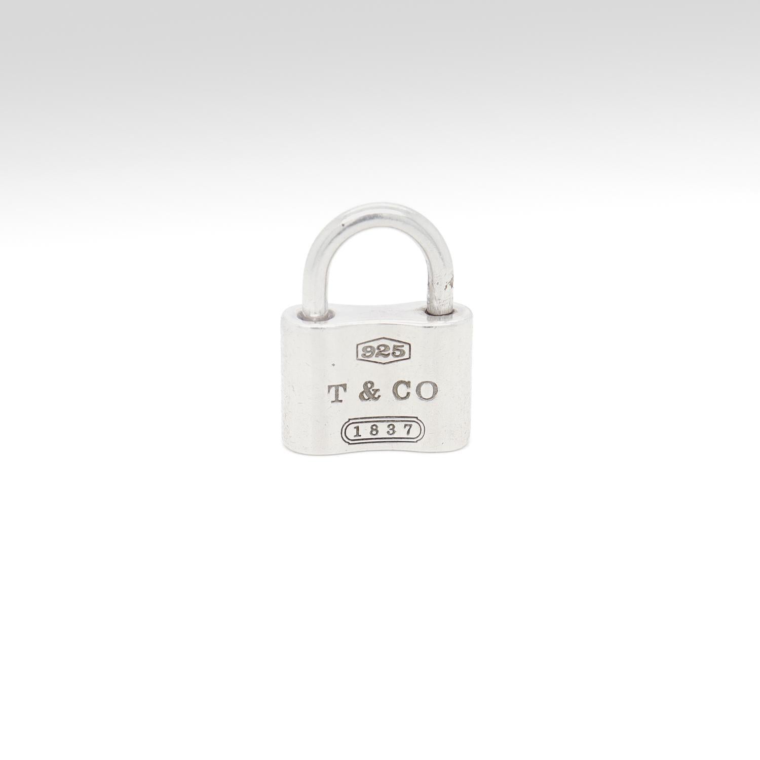 A fine padlock charm or pendant.

In sterling silver. 

By Tiffany & Co. 

The curved post pulls oven and swivels to attach to a chain or bracelet.

Marked T & CO for Tiffany and Company, 925 for sterling silver fineness, and with the 1837