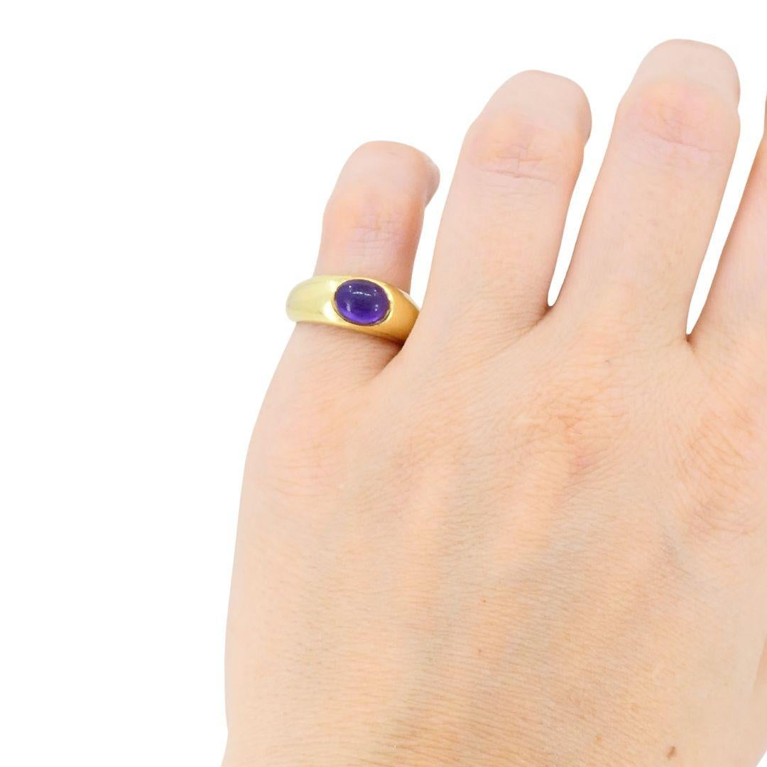 Questo anello vintage con ametista cabochon di Tiffany & Co. è realizzato in oro giallo 18 carati e reca il timbro Tiffany & Co. Risalente agli anni '80, il design presenta una fascia liscia e lucida con al centro un'ametista ovale tagliata a