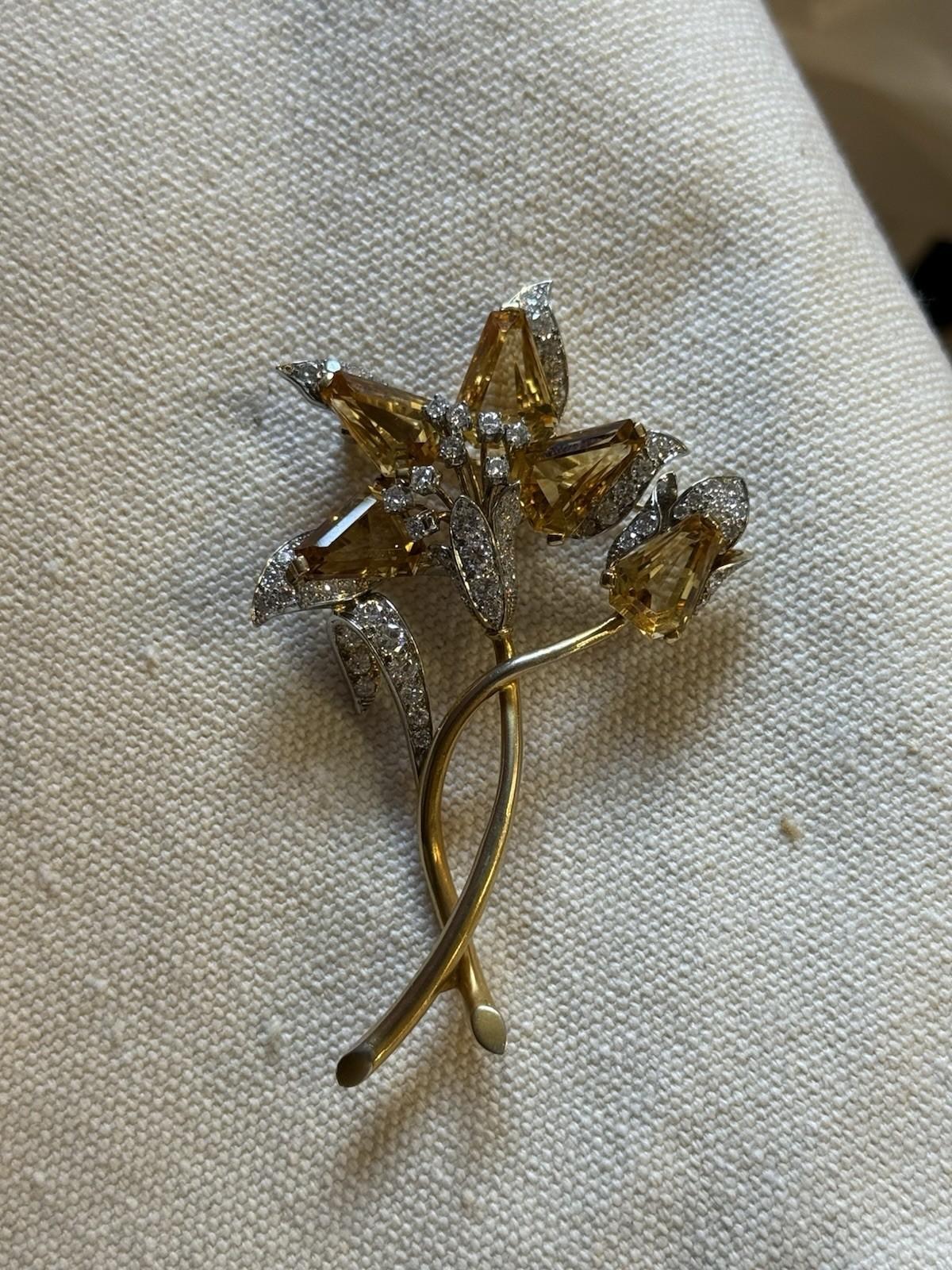 A rare and elegant vintage brooch by Tiffany & Co., beautifully modeled as a stylized flower. Crafted in 18-karat yellow gold, the piece is set with five richly faceted citrine petals of vivid golden-orange hue, complemented by diamond-set leaves