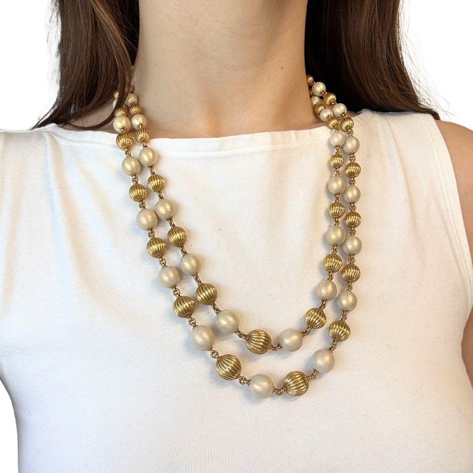 Questa collana vintage con doppio filo di perline di Tiffany & Co. è realizzata in oro giallo 18 carati con perline di smalto bianco alternate. La collana presenta un design graduato, con le dimensioni delle perle che aumentano verso il centro e si