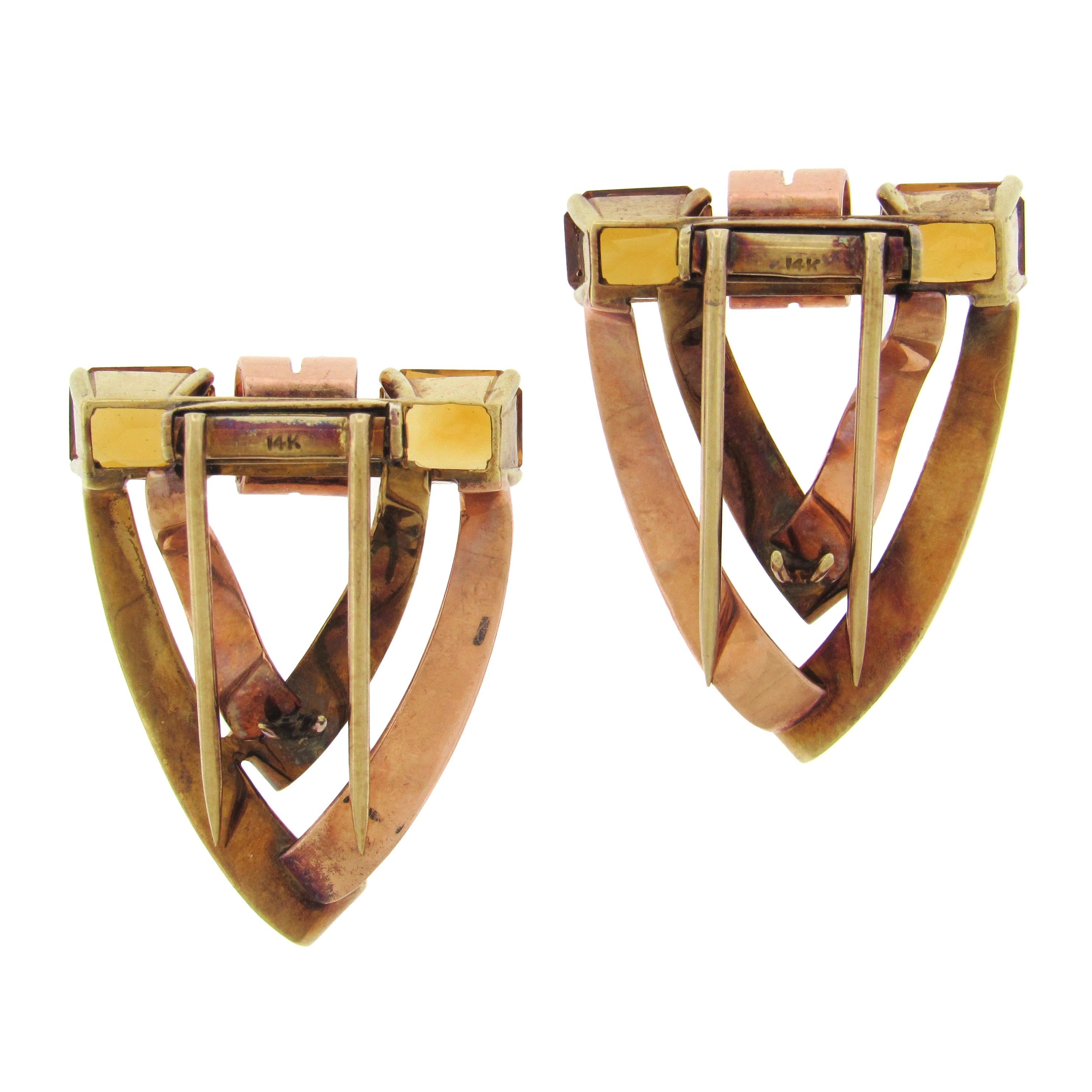 Vintage dress clips, circa 1940’s, by Tiffany & Co, in ribbon curl chevrons of 14K rose and yellow gold, set at top with radiant emerald-cut citrines, approx. 4 carats tw. The dress clips measure 1″ x 1-1/4″ x 1/2″. 
