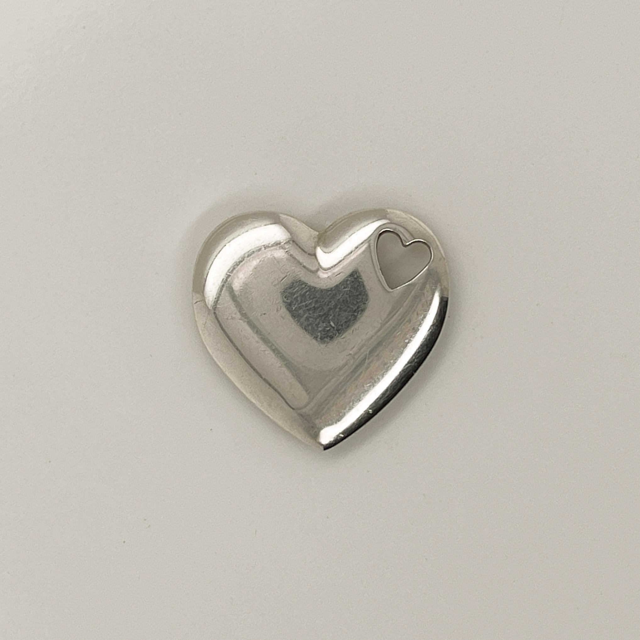 A fine Tiffany & Co heart pendant.

In sterling silver.

With a cut-out heart for the chain to one lobe.

Great Tiffany design!

Date:
20th Century

Overall Condition:
It is in overall good, as-pictured, used estate condition with some very fine &