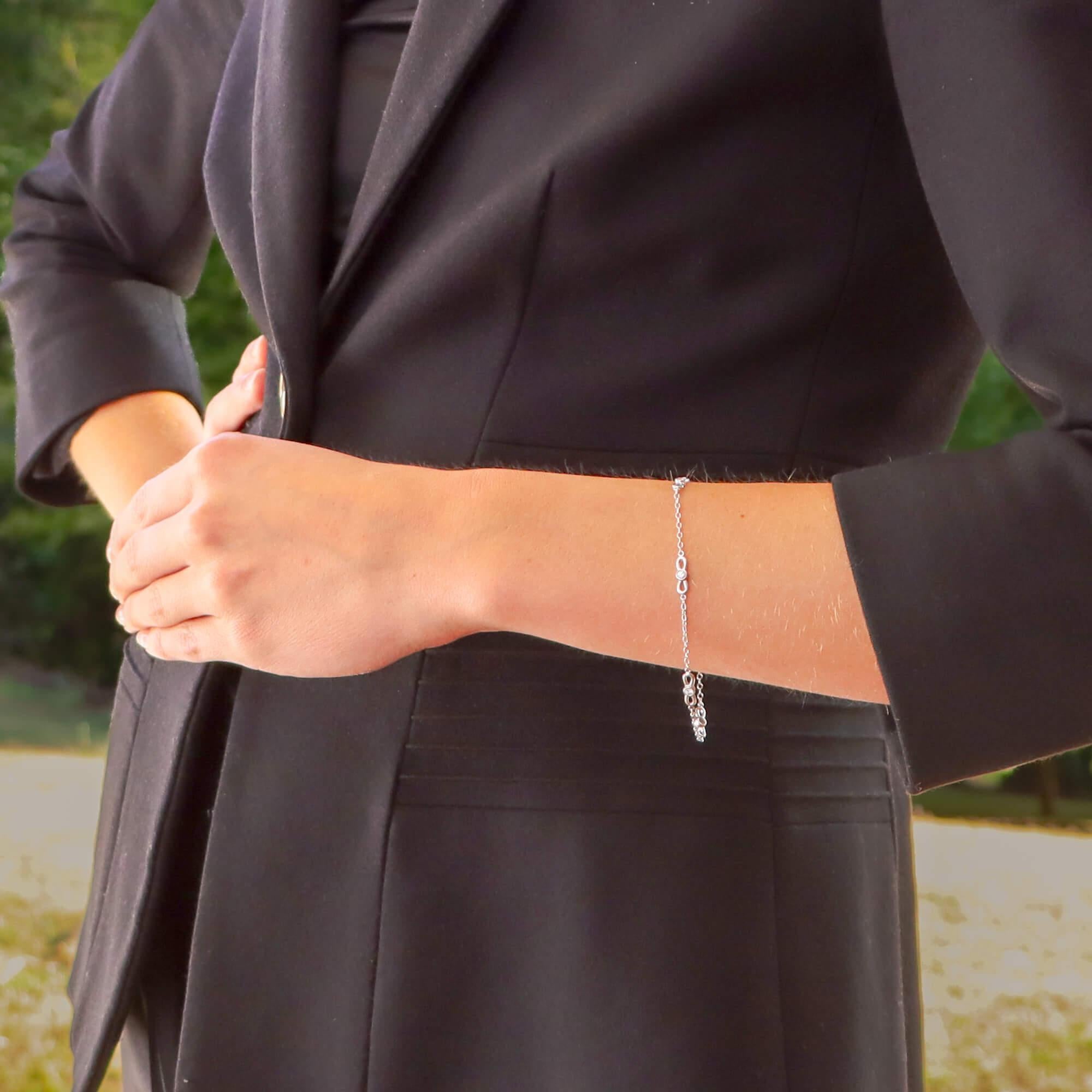 Un bracelet simple mais élégant en or blanc 18 carats de Tiffany & Co. avec des diamants en forme de nœud papillon.

Le bracelet est composé de cinq motifs de nœuds papillon, chacun étant serti au centre d'un diamant rond de taille brillant