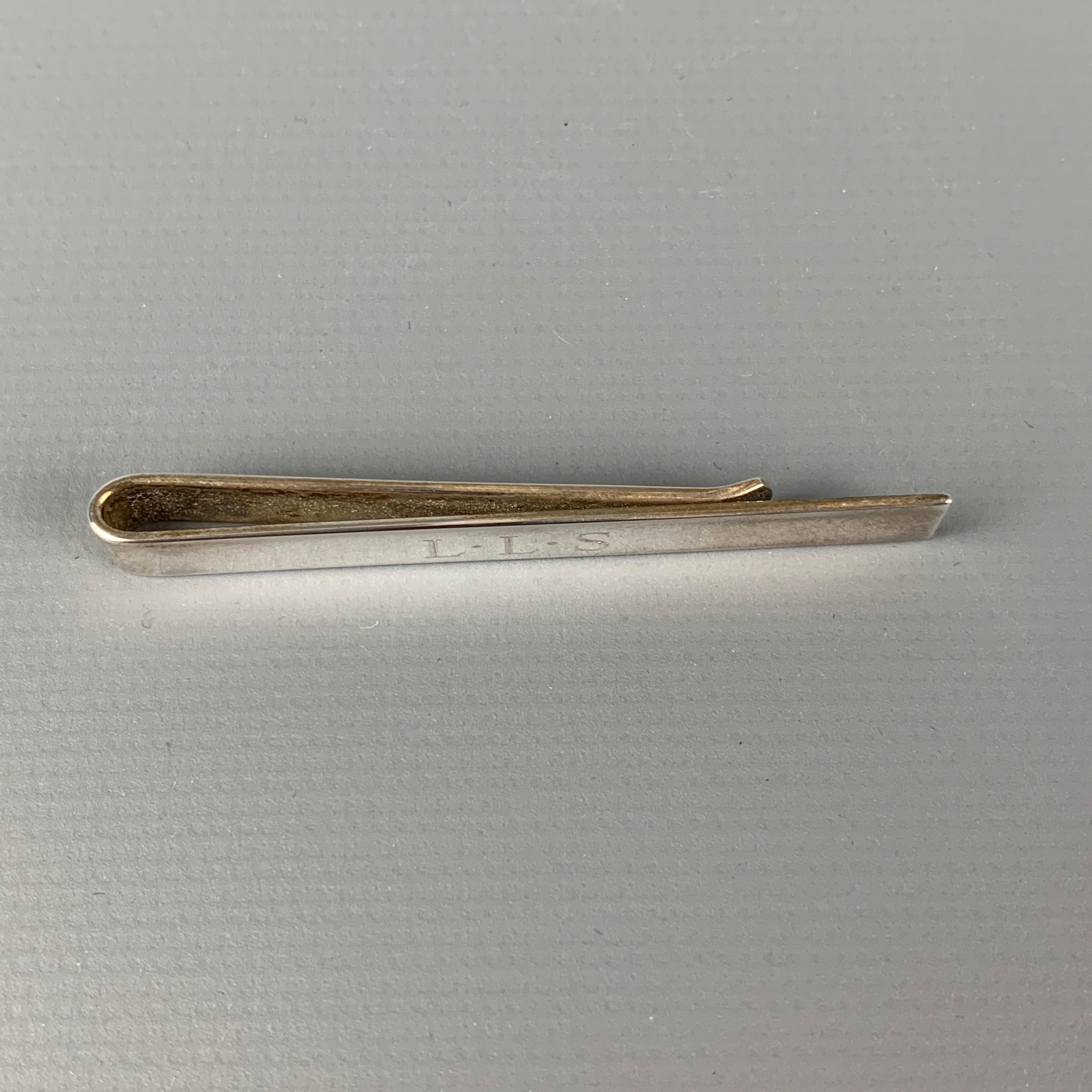 Vintage TIFFANY & CO. tie bar comes in a sterling silver with a engraved 'LLS' design. Includes pouch. 

Very Good Pre-Owned Condition.
Original Retail Price: $250.00

Measurements:

Length: 2 in. 