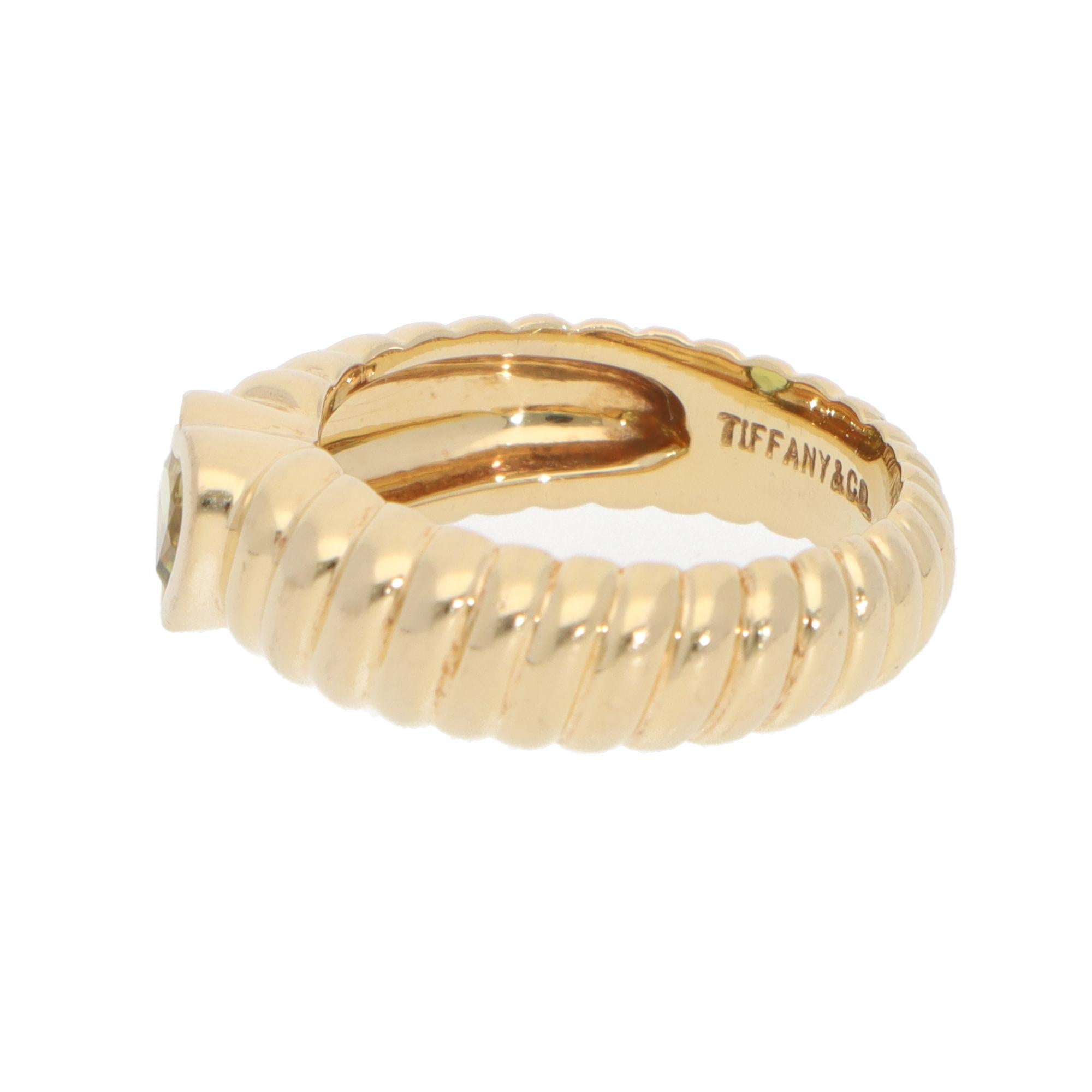 A stylish vintage Tiffany & Co. friendship peridot ring set in 18k yellow gold.

The ring is composed of a heart-shaped mixed-cut bright green peridot that is bezel set securely in a ribbed yellow gold band. The peridot stands out because of the