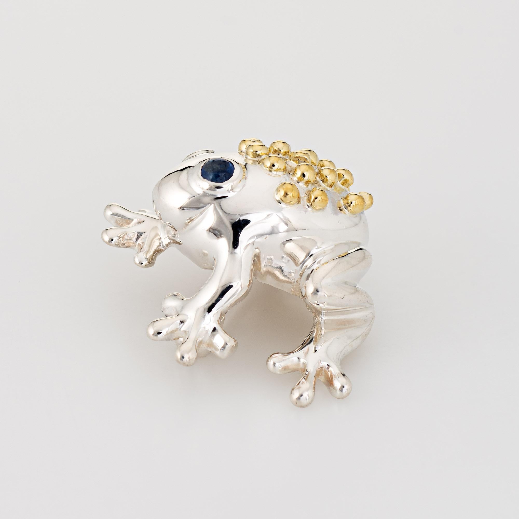 Finely detailed vintage Tiffany & Co frog brooch crafted in sterling silver & 18k yellow gold (circa 1990s). 

The sweet little frog features a textured back in 18k yellow gold with cabochon set blue sapphire eyes. Small in scale, the brooch is