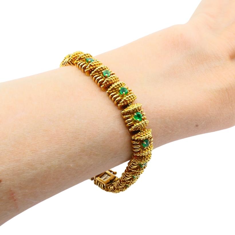Dieses Armband im Vintage-Stil von Tiffany & Co. zeichnet sich durch ein kühnes, strukturiertes Design aus 18-karätigem Gold aus, das mit leuchtend grünen Smaragden verziert ist. Das Armband besteht aus gegliederten quadratischen Gliedern, in deren
