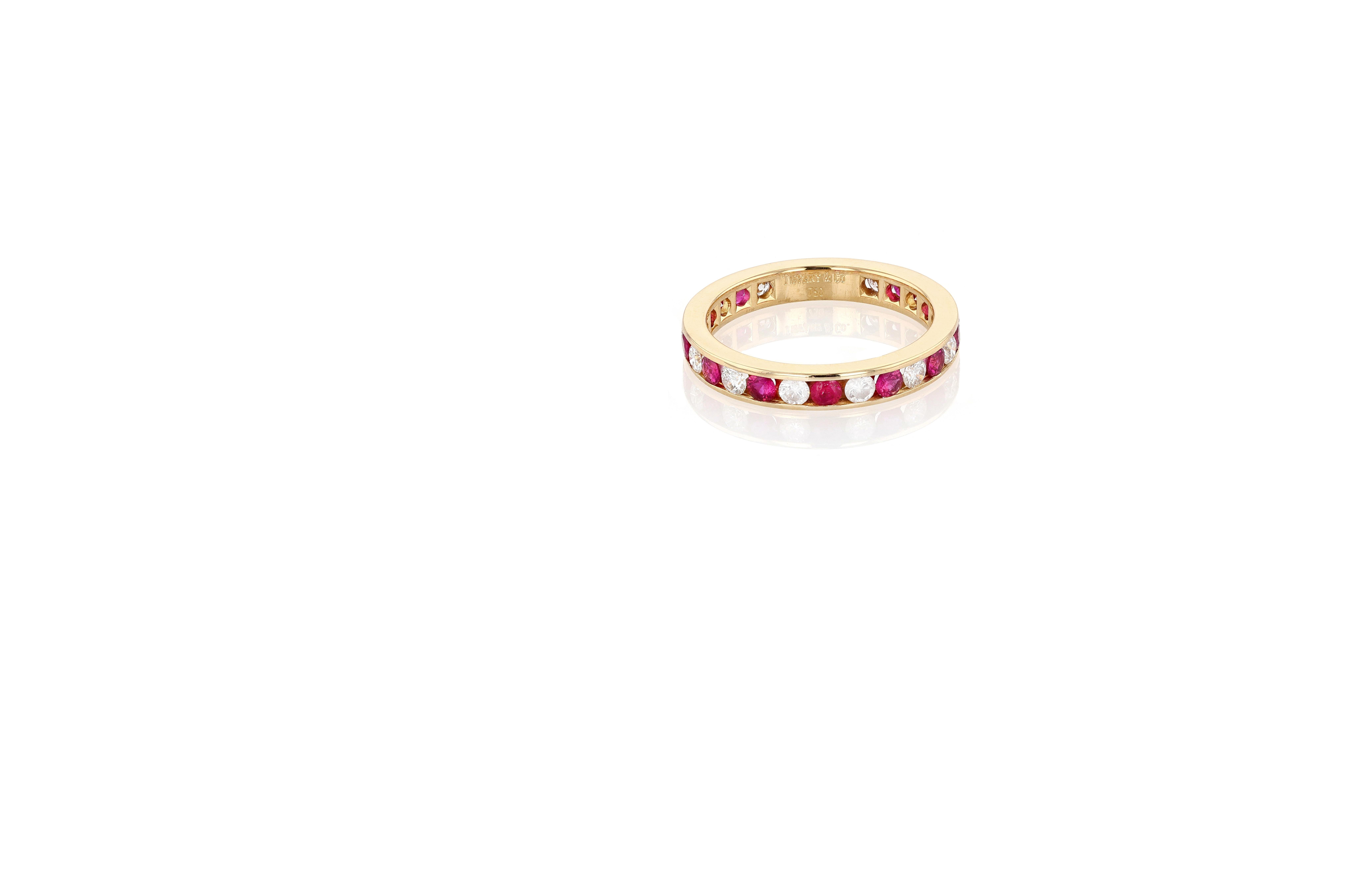Anillo de la eternidad vintage Tiffany & Co. de oro amarillo de 18 quilates, diamantes y rubíes. Las piedras están engastadas en canal y la banda está perforada en la parte posterior para permitir el paso de la luz a través de las piedras, excepto
