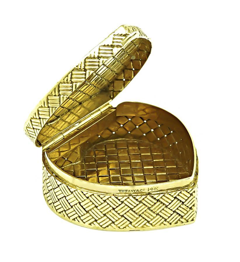 This is a charming 14k yellow gold heart pill box by Tiffany & Co. The pill box measures 34mm by 34mm and weighs 25.5 grams. The pill box is signed TIFFANY&Co 14K.