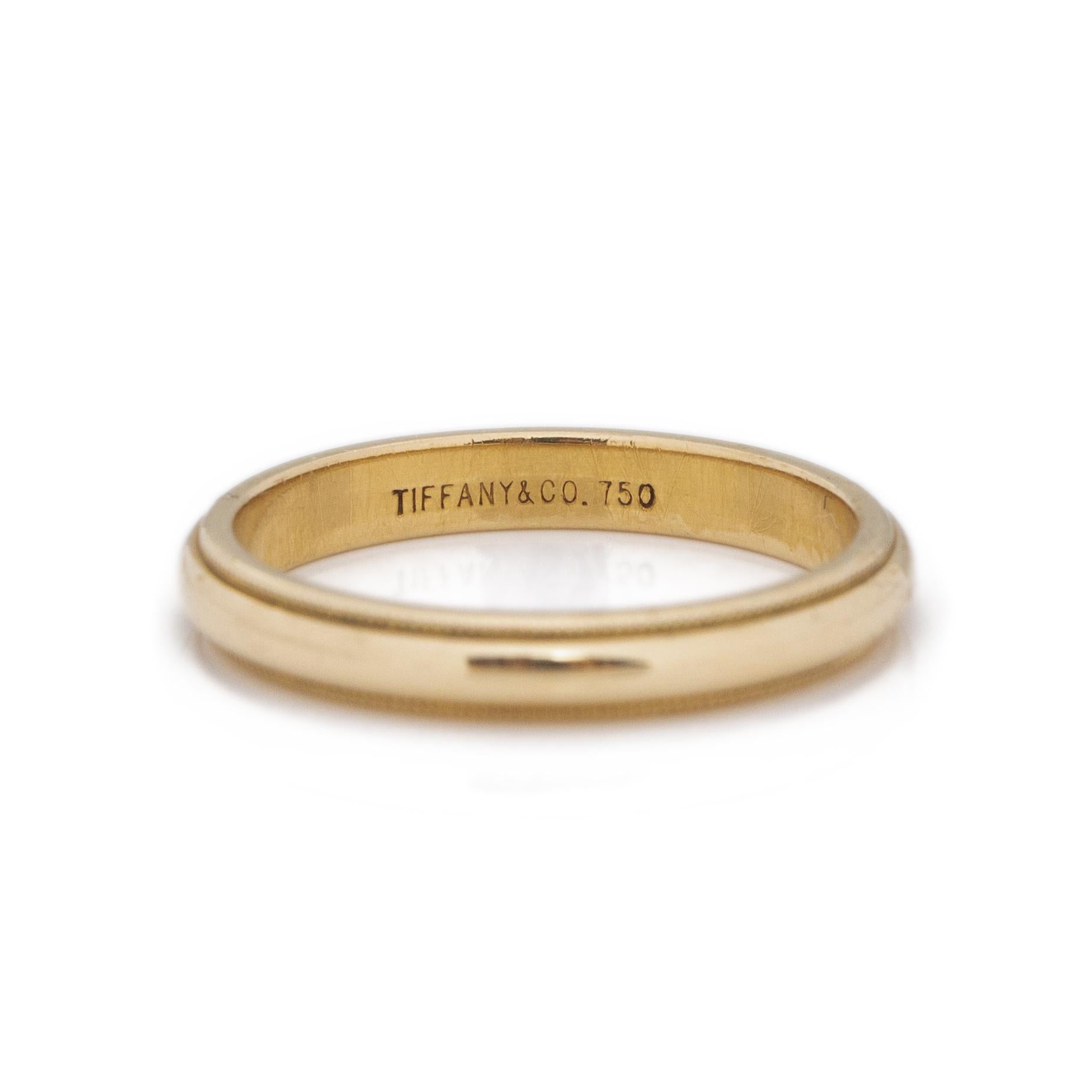 This Tiffany & Co. made beauty is in excellent condition and has a wonderful minimalist vibe to it. Crafted in 18K yellow gold, the shine and color in this piece is breathtaking. In the middle of to delicately carved milgrain borders is a smooth