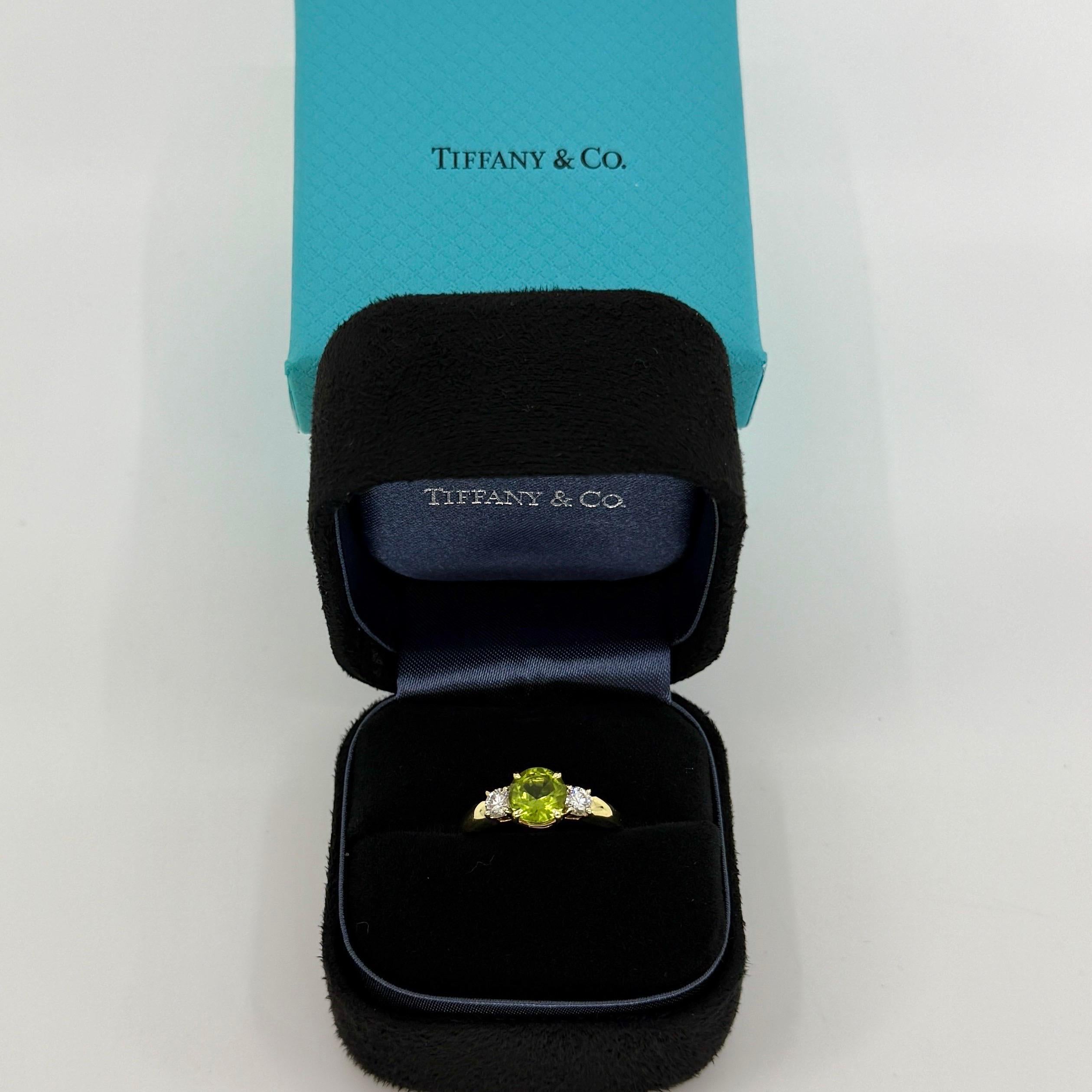 Vintage Tiffany & Co Round Cut Vivid Green Peridot und Diamant 18k Gelbgold Drei Stein Ring.

Dieser klassische Ring mit drei Steinen besteht aus einem 6,8 mm großen, rund geschliffenen, lebhaft rosafarbenen Peridot - etwa 1,20 Karat. 
Akzentuiert