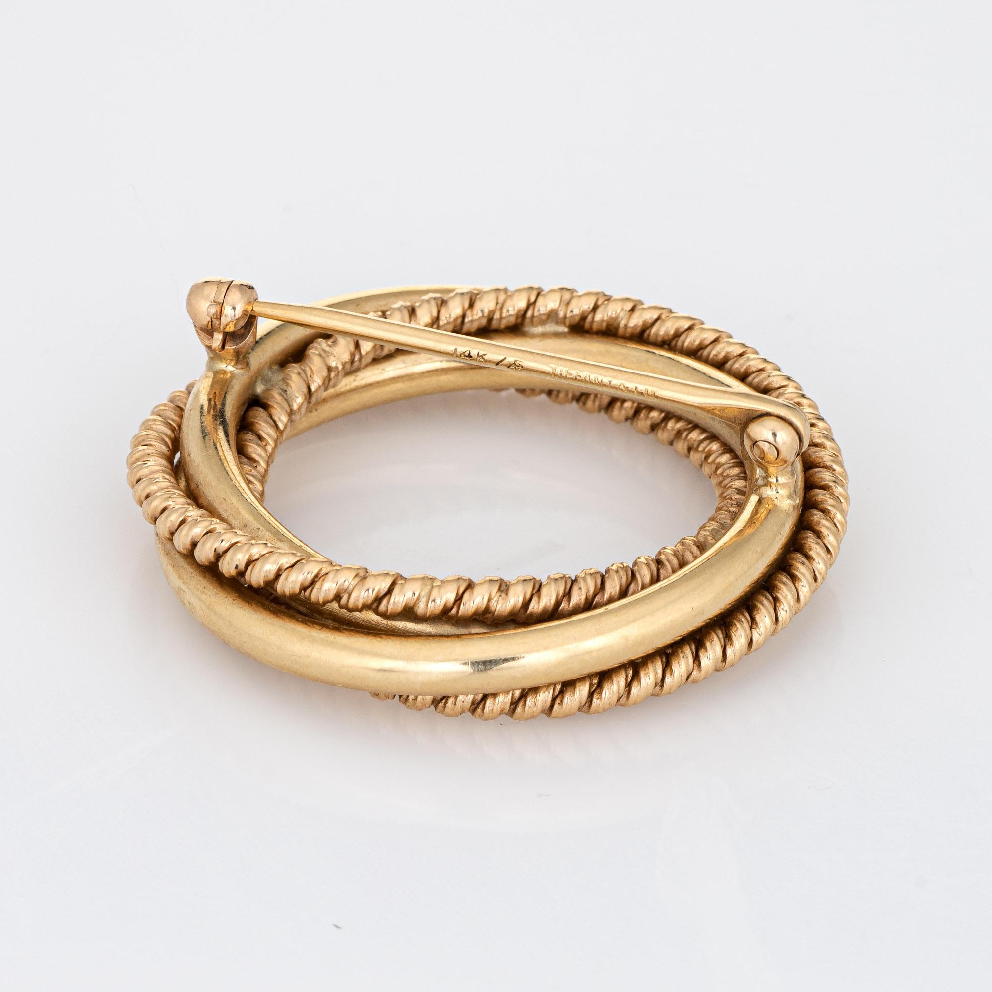 Finely detailed vintage Tiffany & Co infinity knot brooch, crafted in 14 karat yellow gold (circa 1950s to 1960s).  

The brooch is a retired piece and no longer made by Tiffany & Co. The brooch highlights rope and polished gold details, gracefully