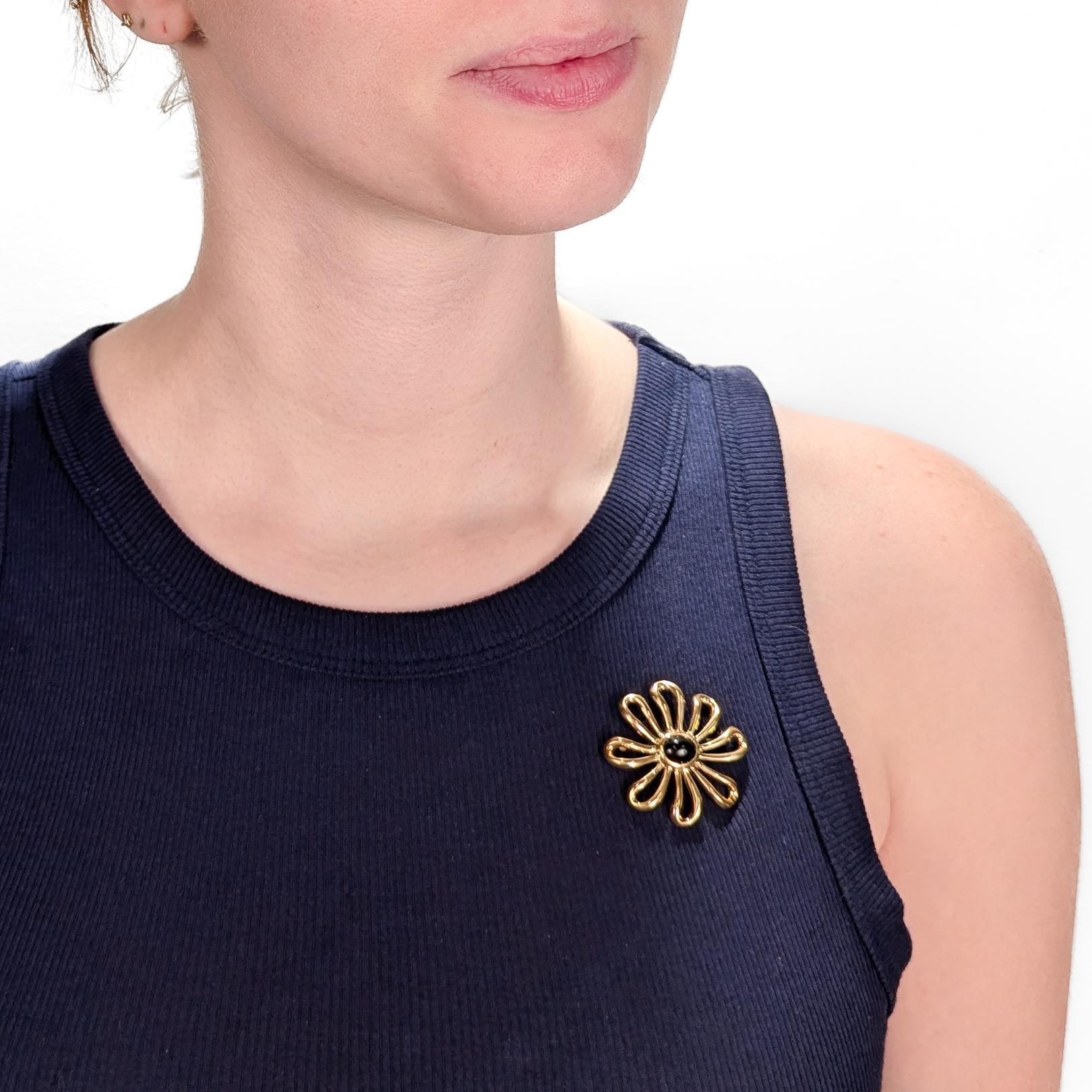 A fine signed 1980's gold and onyx brooch.

In 18 karat yellow gold.

By Tiffany & Co.

Designed by Paloma Picasso.

In the form of an flower or daisy with openwork petals and center-set with a bezel-set oval onyx cabochon.

Fully marked to the