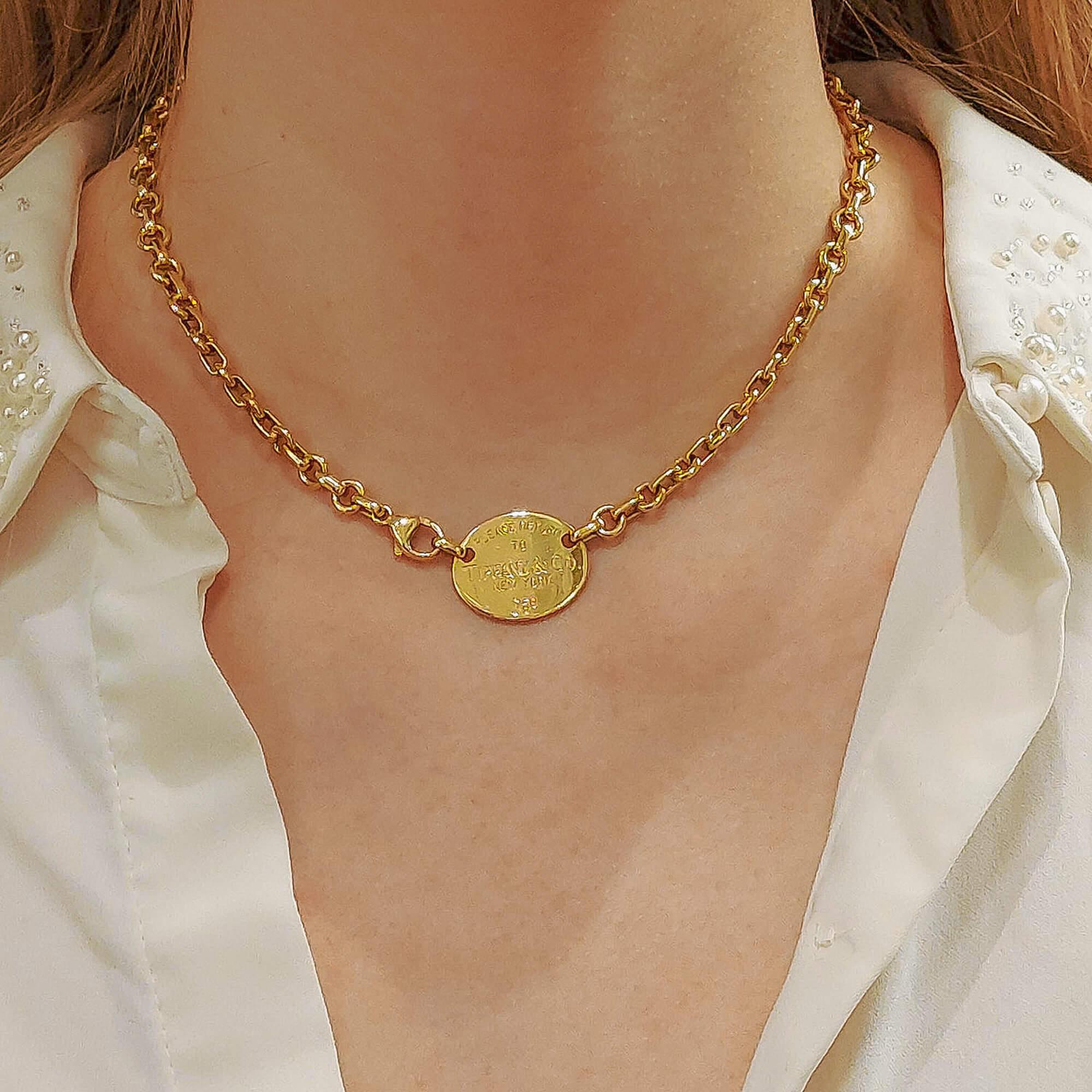 An iconic 'Please Return to Tiffany' Tiffany & Co. necklace in solid 18k yellow gold. The necklace depicts the iconic 'Return to Tiffany' slogan upon a yellow gold shield which sits nicely on the neck (piece in worn photo has been adjusted for