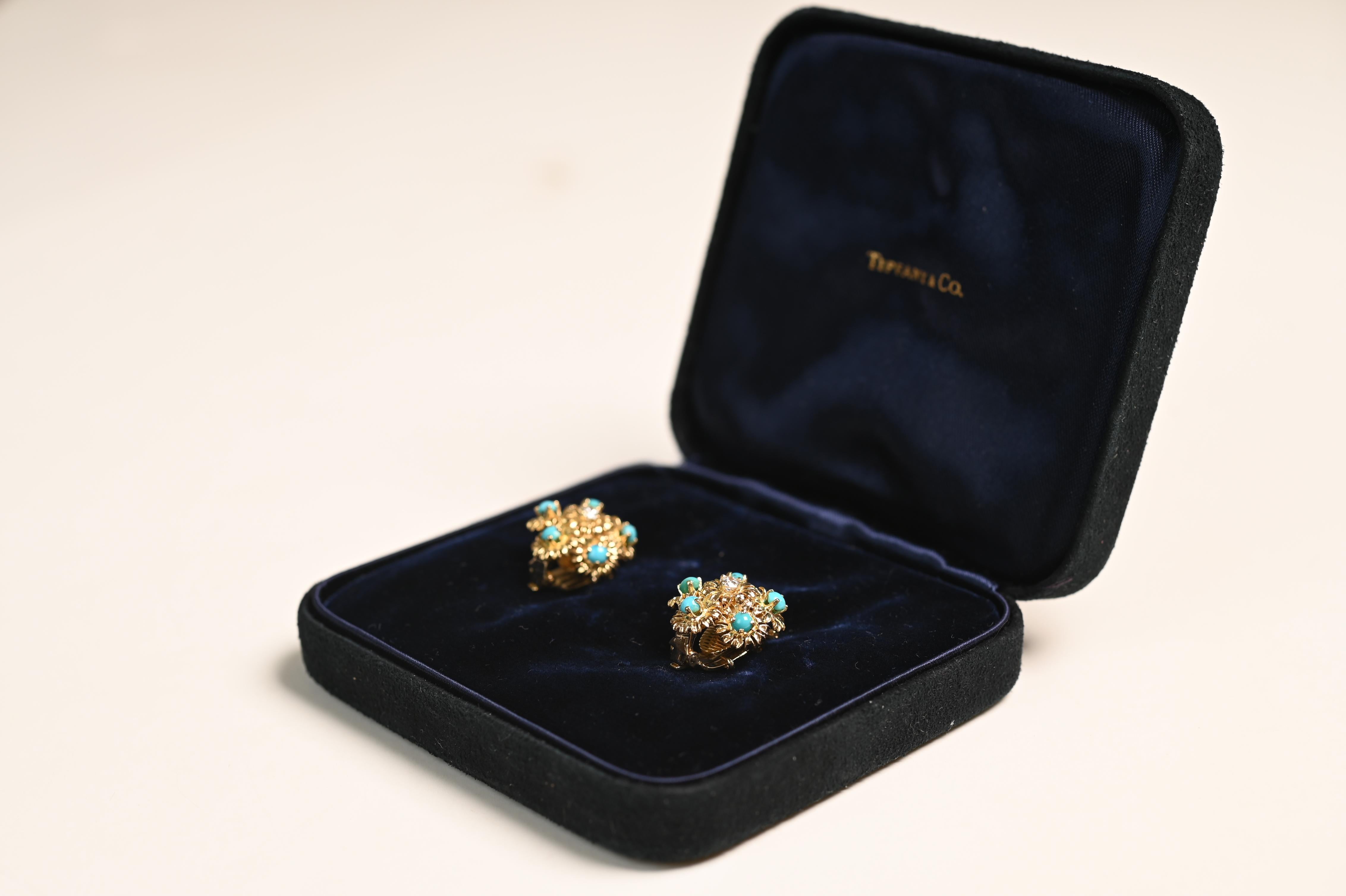 A beautiful and rare pair of vintage Tiffany & Co. earrings crafted in rich 18k yellow gold. These stunning earrings feature a unique textured floral design, each centered with a round brilliant cut diamond surrounded by five vibrant turquoise