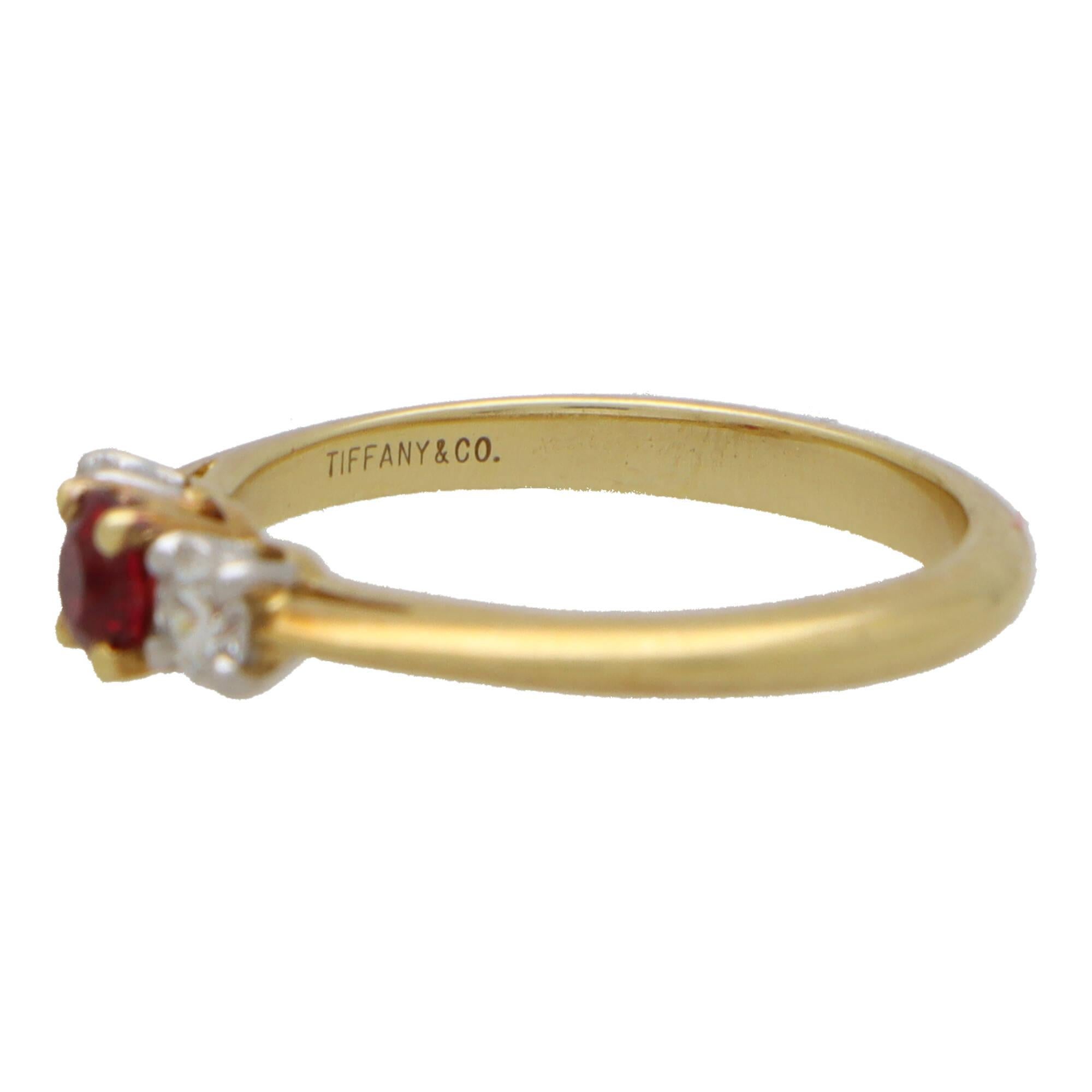 A beautiful ruby and diamond trilogy engagement ring set in 18k yellow gold and platinum.

This classic engagement ring design is centrally set with a stunning round cut ruby which is four claw set in an open back triple setting. The ruby is then