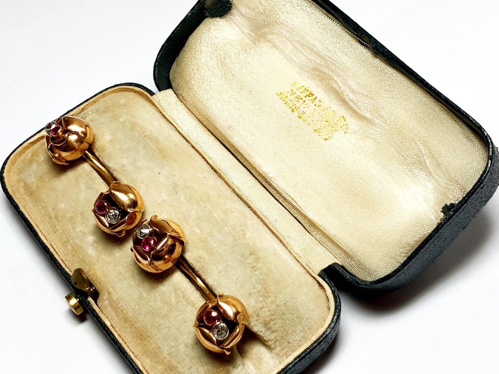 A pair of vintage Tiffany & Co. cufflinks, set with a flower to each end, connected by a curved bar link, each flower is set with a round cut ruby and old cut diamond, mounted in 18ct yellow gold, signed by Tiffany & Co, circa 1940's.