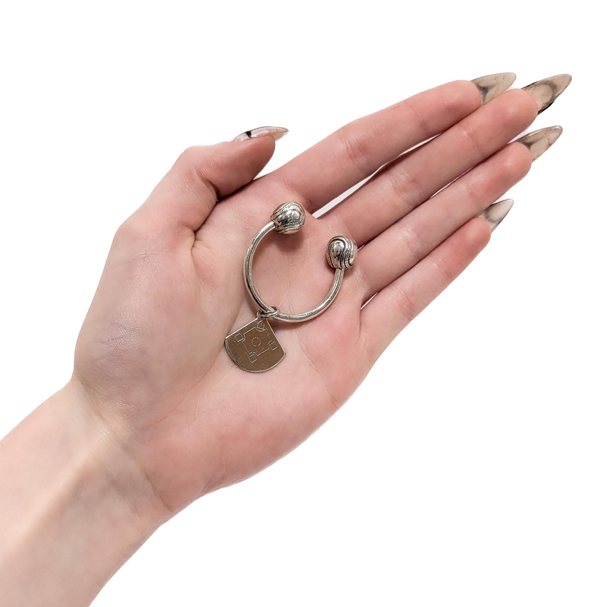 Un raffinato portachiavi d'argento firmato.

Da Tiffany & Co.

In argento sterling.

L'anello ha un charm con diamante di baseball inciso ed entrambe le estremità con terminali figurati di baseball. 

La palla da baseball contrassegnata con una 