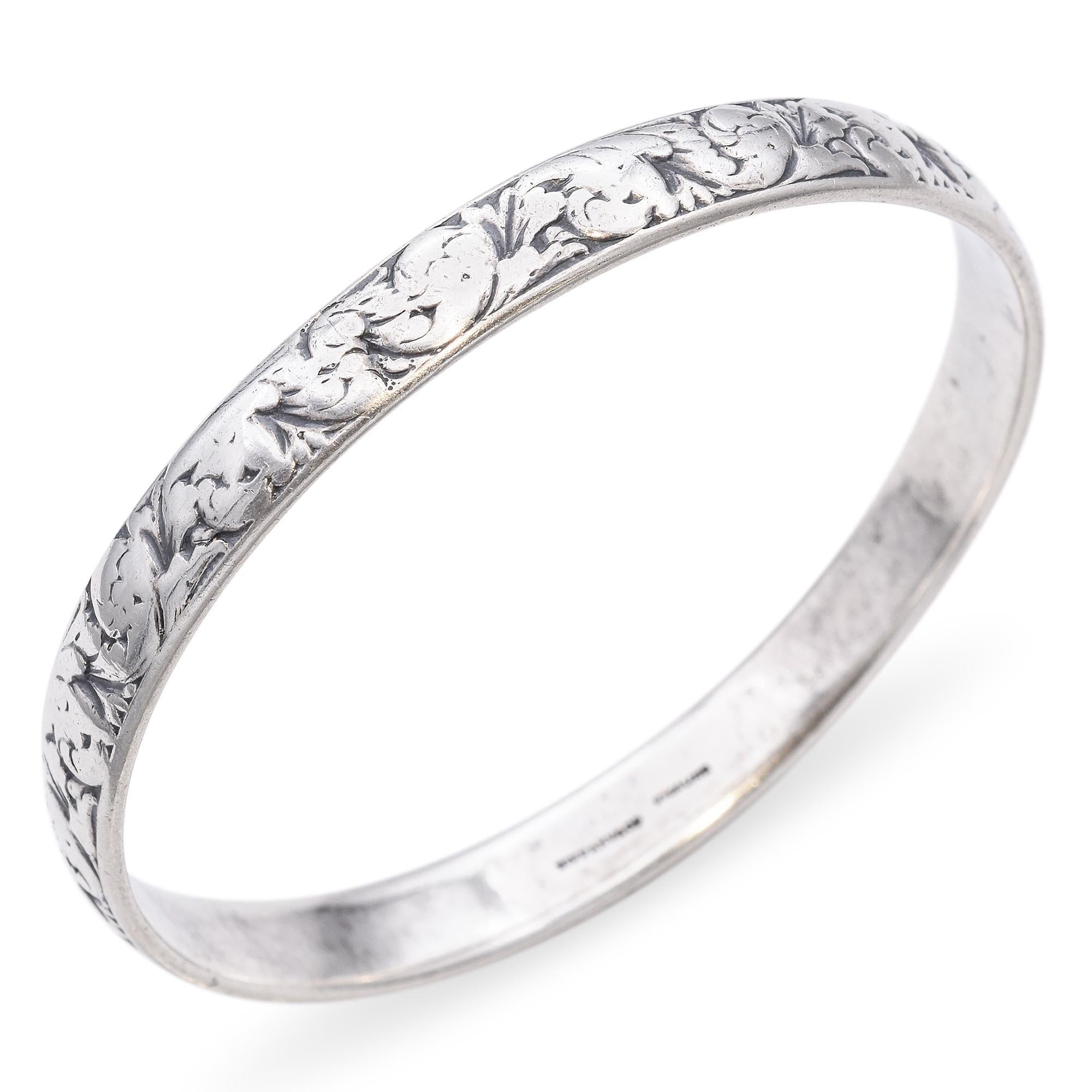 This sterling silver bangle bracelet by Tiffany & Co. features an intricate floral design etched along its surface. The delicate pattern is both subtle and elegant, showcasing the brand's renowned craftsmanship. A timeless piece that complements any