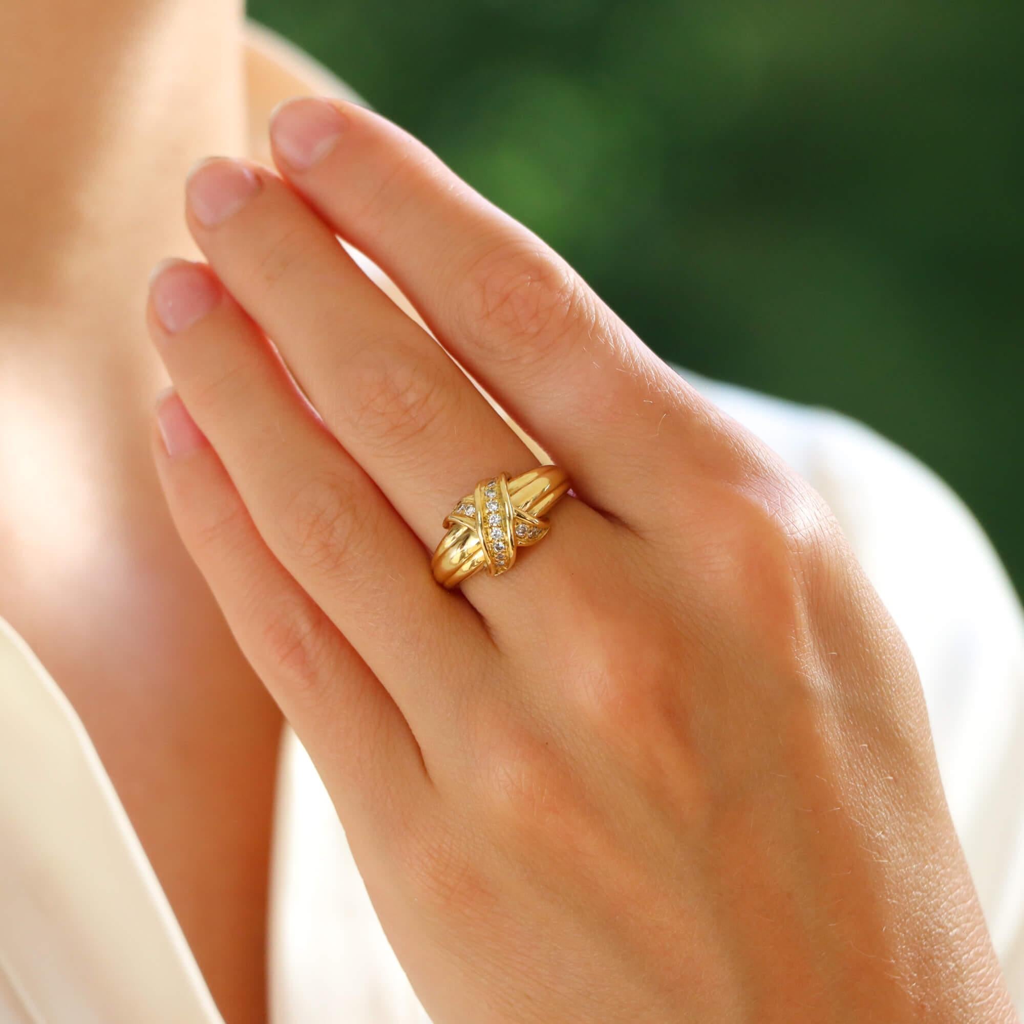 A beautiful vintage Tiffany & Co. signature cross ring in 18k yellow gold.

The ring predominantly features the iconic Tiffany cross motif, set on top of fluted banded shoulders. The cross is pave set throughout with round brilliant cut diamonds.