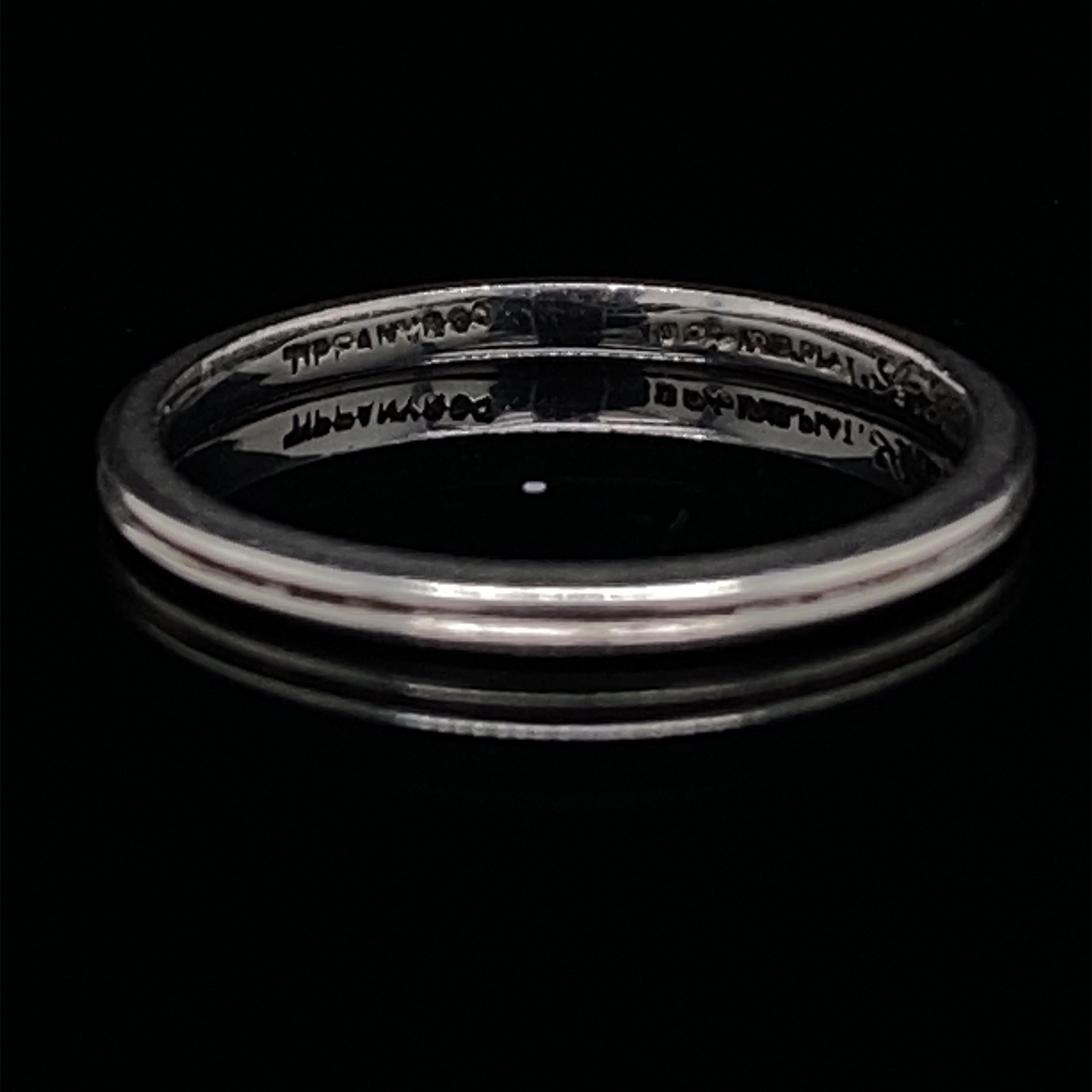 A vintage Tiffany & Co. platinum wedding band, circa 1947.

This elegant fine band has a deep ridged detail to its centre and comprises of platinum and iridium, which was typical for rings of this time period from the United States.

Signed 'TIFFANY