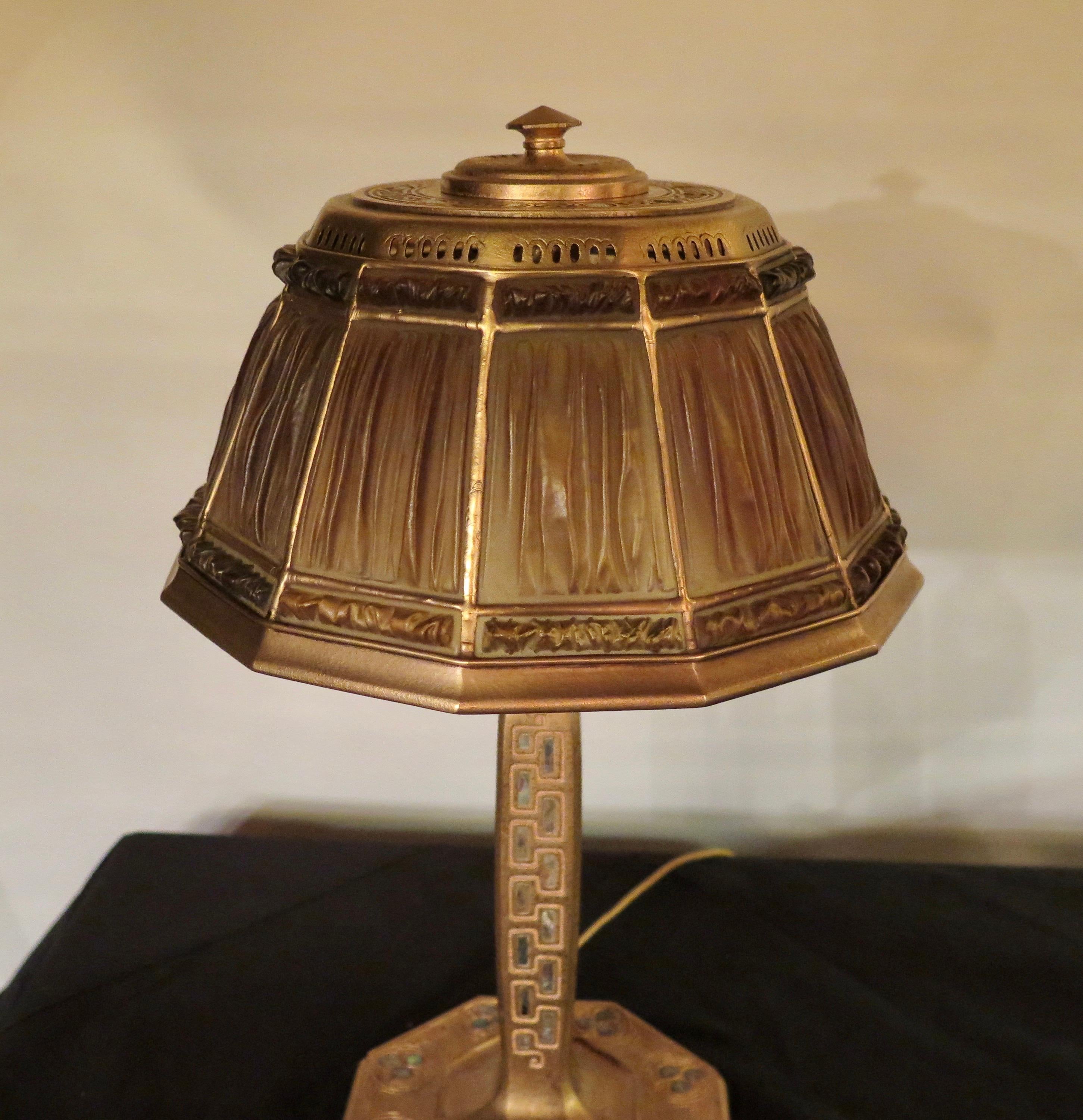 This stunning Tiffany Studios, New York desk lamp dates from the early 20th century. The desk lamp base is beautifully designed in doré bronze decorated with a motif of multiple inlaid pieces of abalone shell. An exquisite amber color linenfold