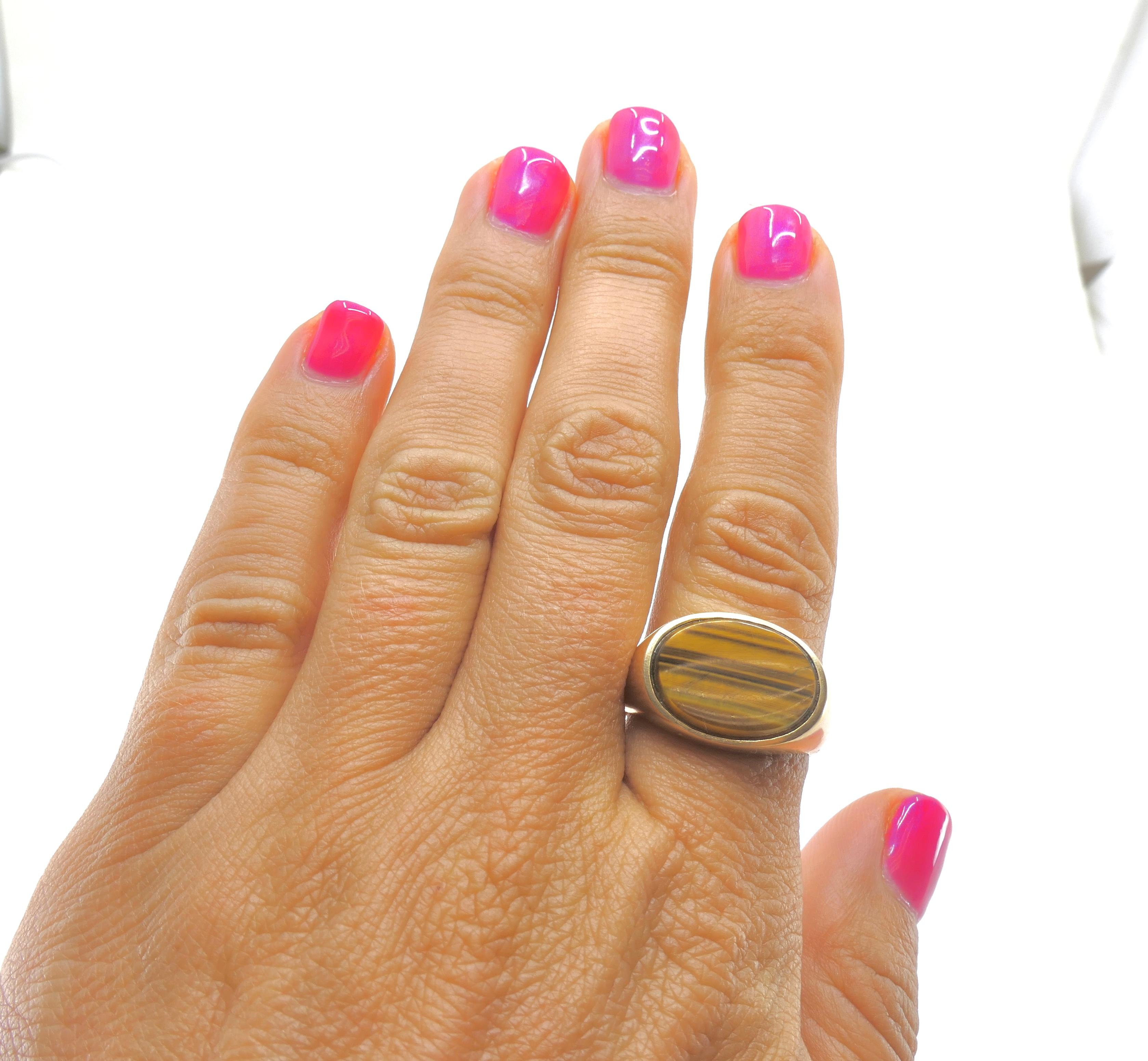 Un sottile ed elegante anello ovale vintage con occhio di tigre in oro 10k.
L'anello presenta un design sottile e minimalista con una gemma occhio di tigre montata orizzontalmente.
La pietra ovale piatta attira l'attenzione con la sua brillantezza,