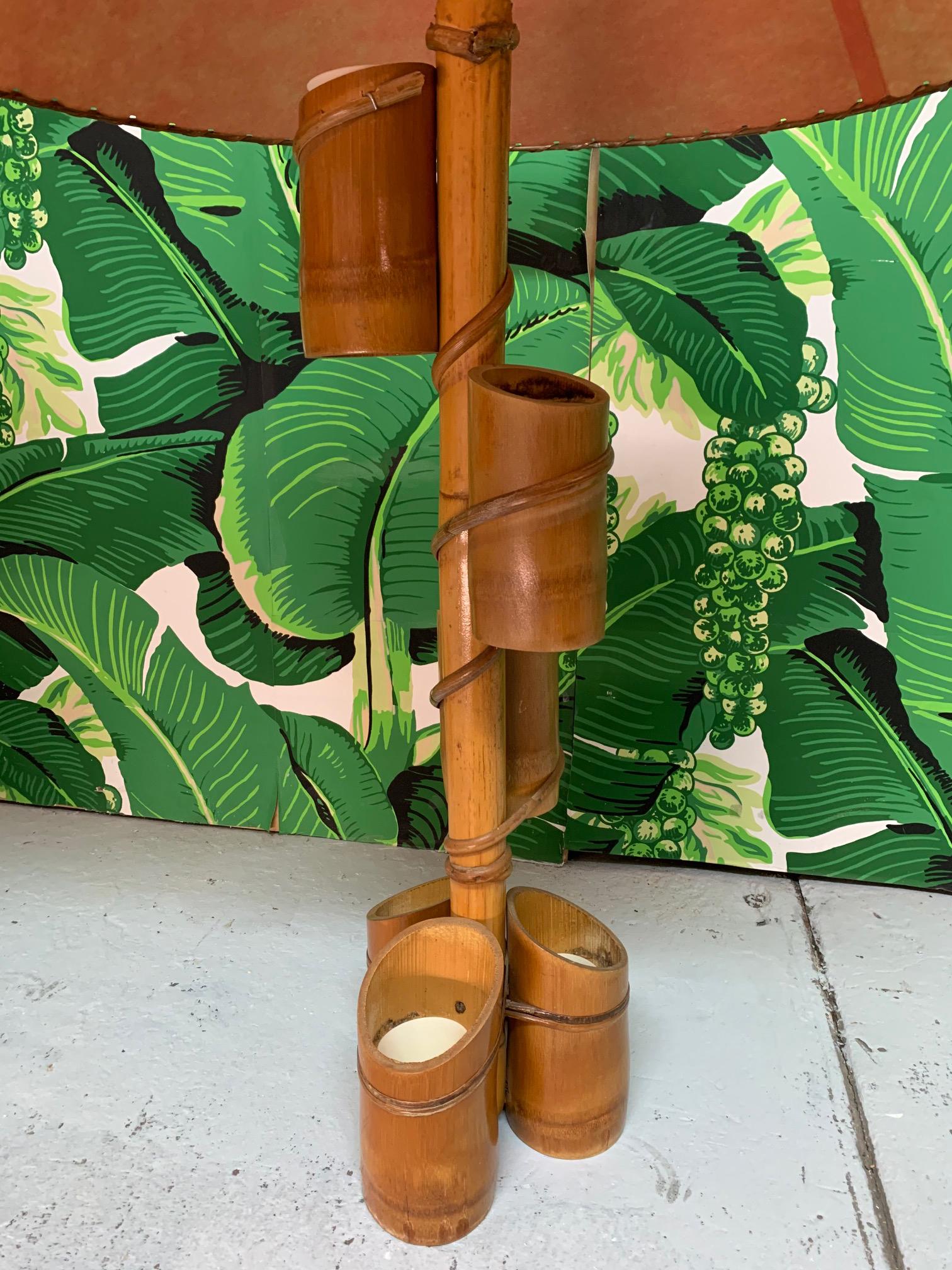 Pair of 1950's Tiki style table lamps feature a bamboo body and fiberglass parchment shades. The main shaft is adorned with small bamboo planters with plastic inserts, perfect for succulents or small bright flowers. Very good vintage condition with