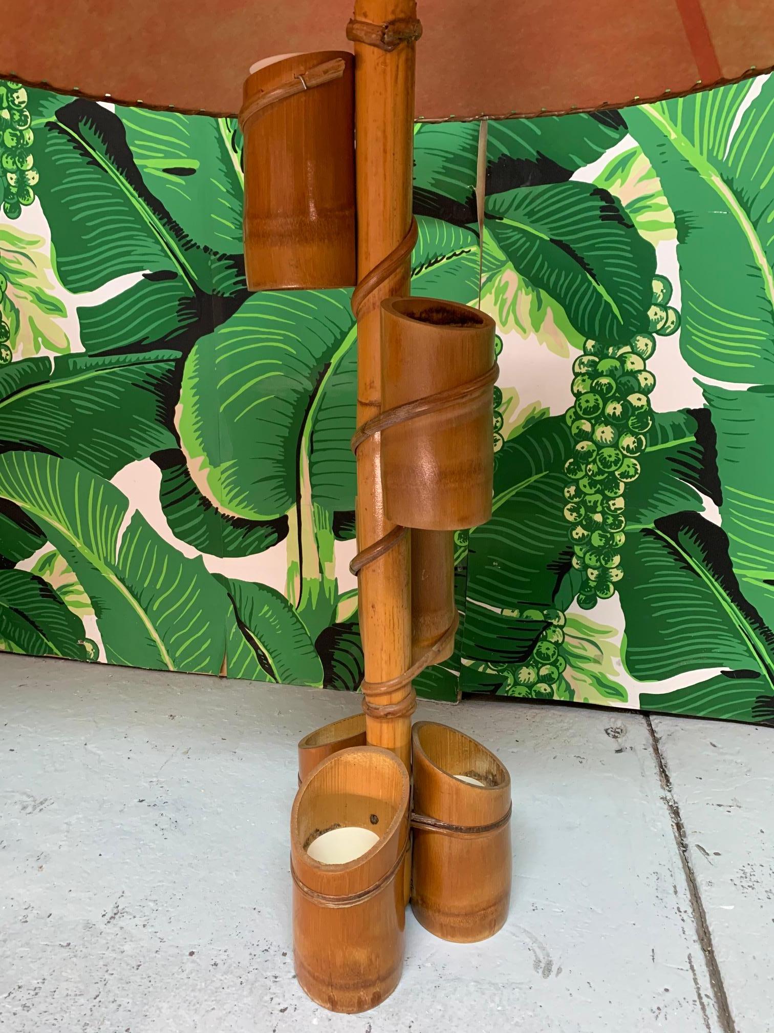 Pair of 1950s Tiki style table lamps feature a bamboo body and fiberglass parchment shades. The main shaft is adorned with small bamboo planters with plastic inserts, perfect for succulents or small bright flowers. Very good vintage condition with