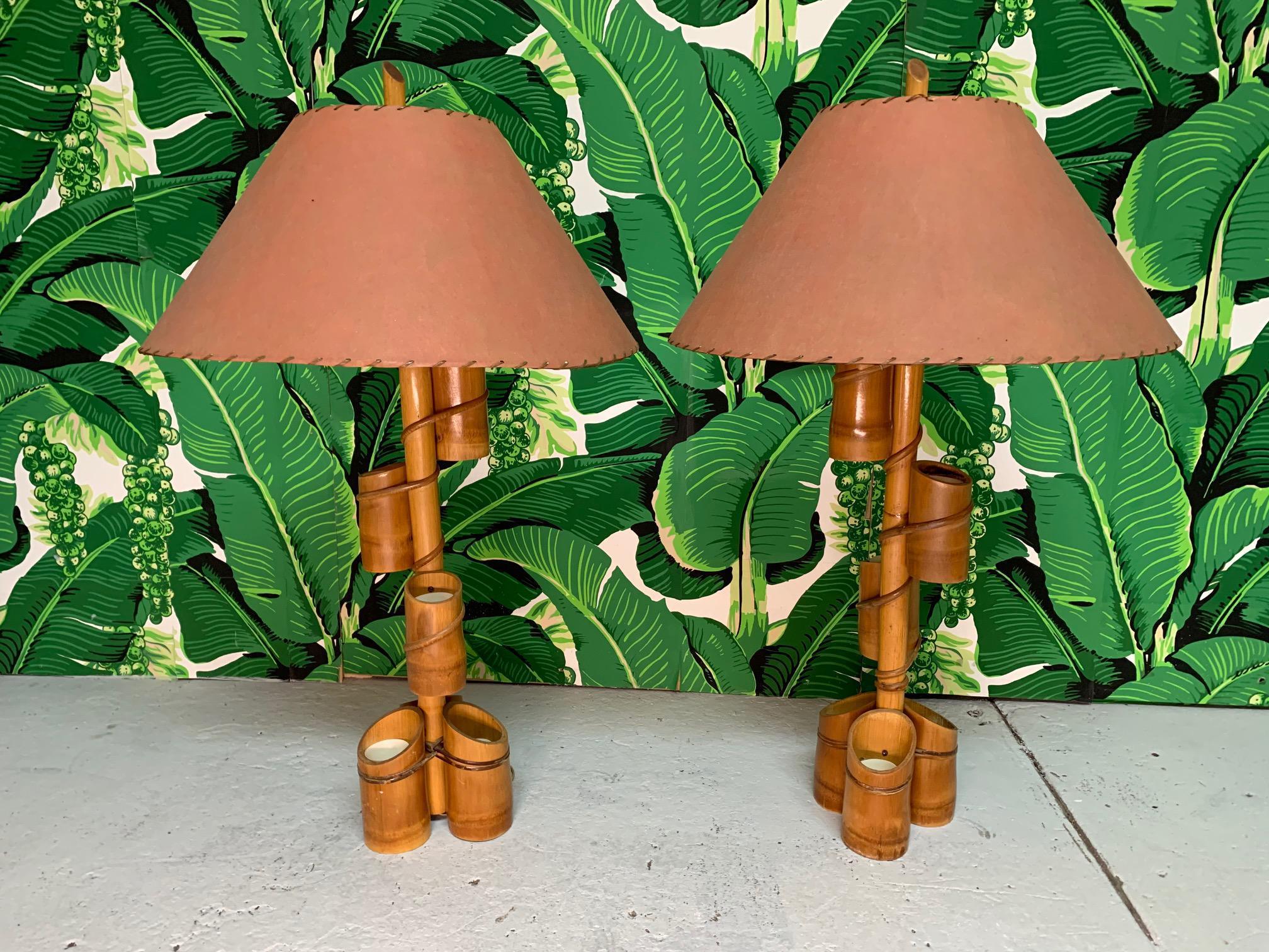 Pair of 1950's Tiki style table lamps feature a bamboo body and fiberglass parchment shades. The main shaft is adorned with small bamboo planters with plastic inserts, perfect for succulents or small bright flowers. Very good vintage condition with
