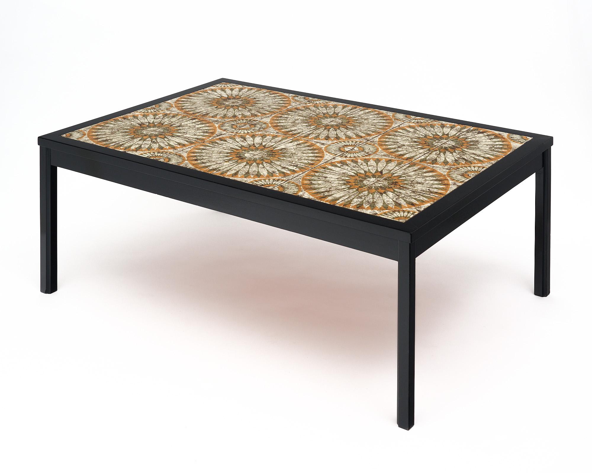 Coffee table with tiled top from Vallauris on the French Riviera. The tables structure is made of ebonized wood that has been finished with a lustrous museum-quality French polish. The top is tiled with hand-crafted and painted terracotta tiles with