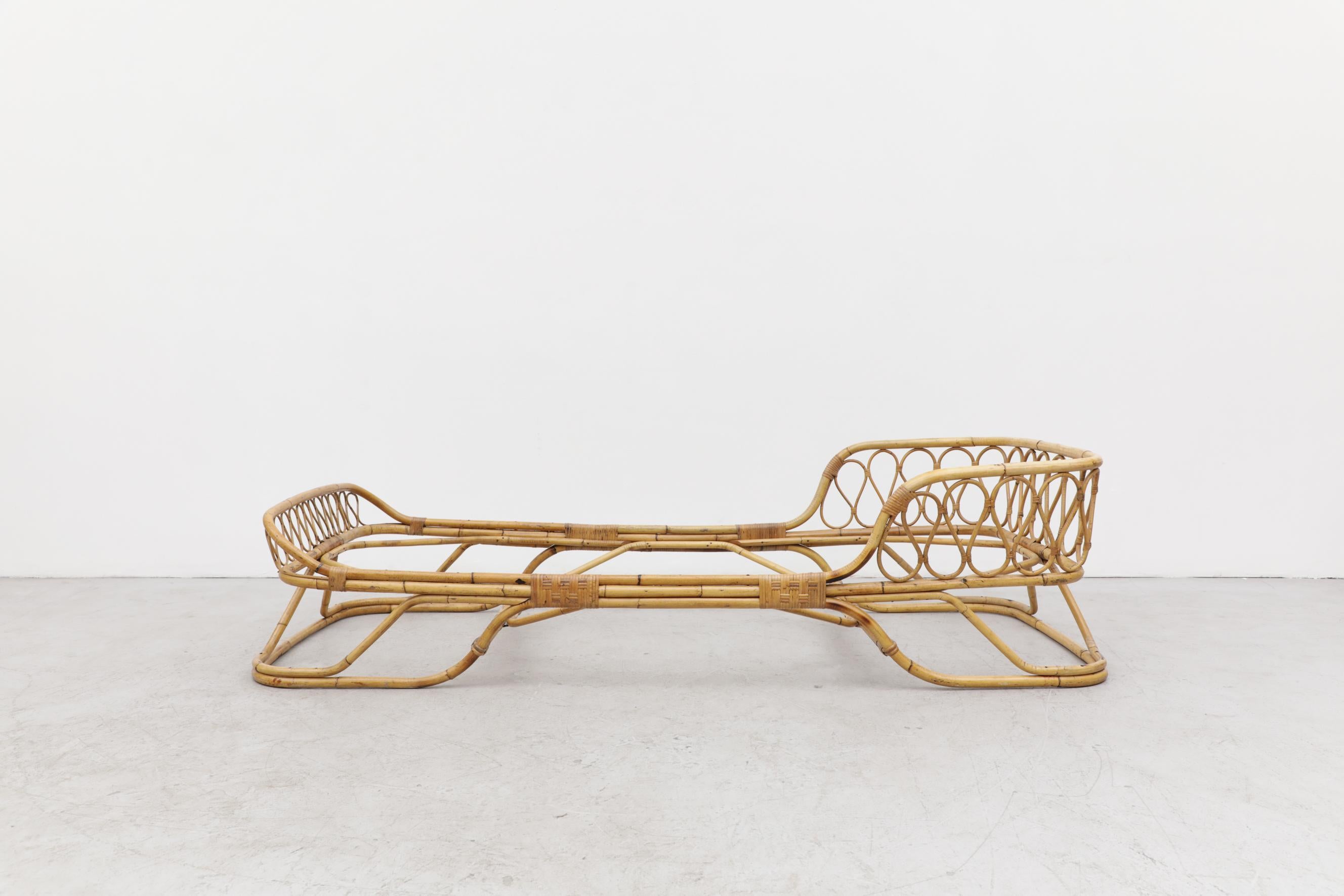 This stunning Mid-Century bent bamboo daybed frame has a sturdy but lightweight sleigh shaped frame and features a decorative crown-like headboard. There is minimal rattan loss and no structural damage. It is in original condition with wear that's