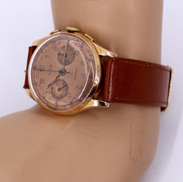 A vintage 18K rose gold chronograph wristwatch by Titus. Featuring a rose gold dial with art deco style numerals, this mid-century timepiece is sophisticated as well as sporty. The subsidiary dials are detailed with an engine turned look. Hosting a