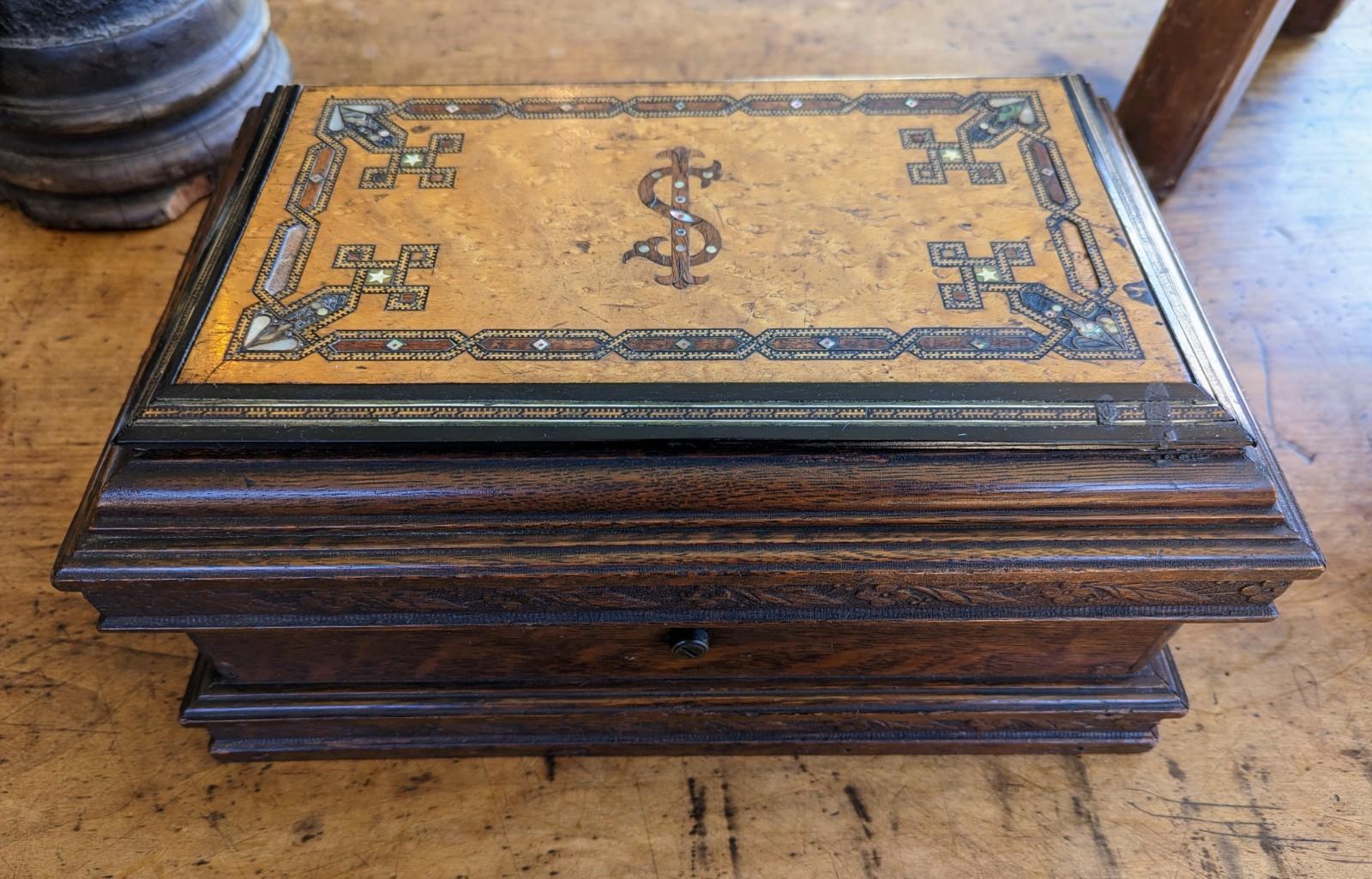 Intriguing antique hand crafted wood box with marquetry top. This decorative box features paua shell and mother of pearl inlay, there are also two secret compartments which makes this a unique collectable piece! The top features a design that looks