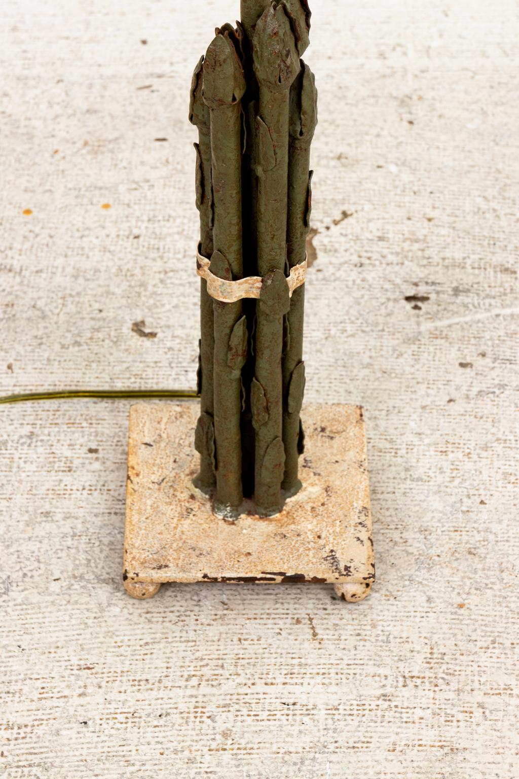 Circa early 20th century vintage tole table lamp in the shape of a bundle of standing asparagus on a square base with ball feet. The square base measures 5.00 Inches by 5.00 Inches. The height of the lamp measures 19.00 Inches to the top of the