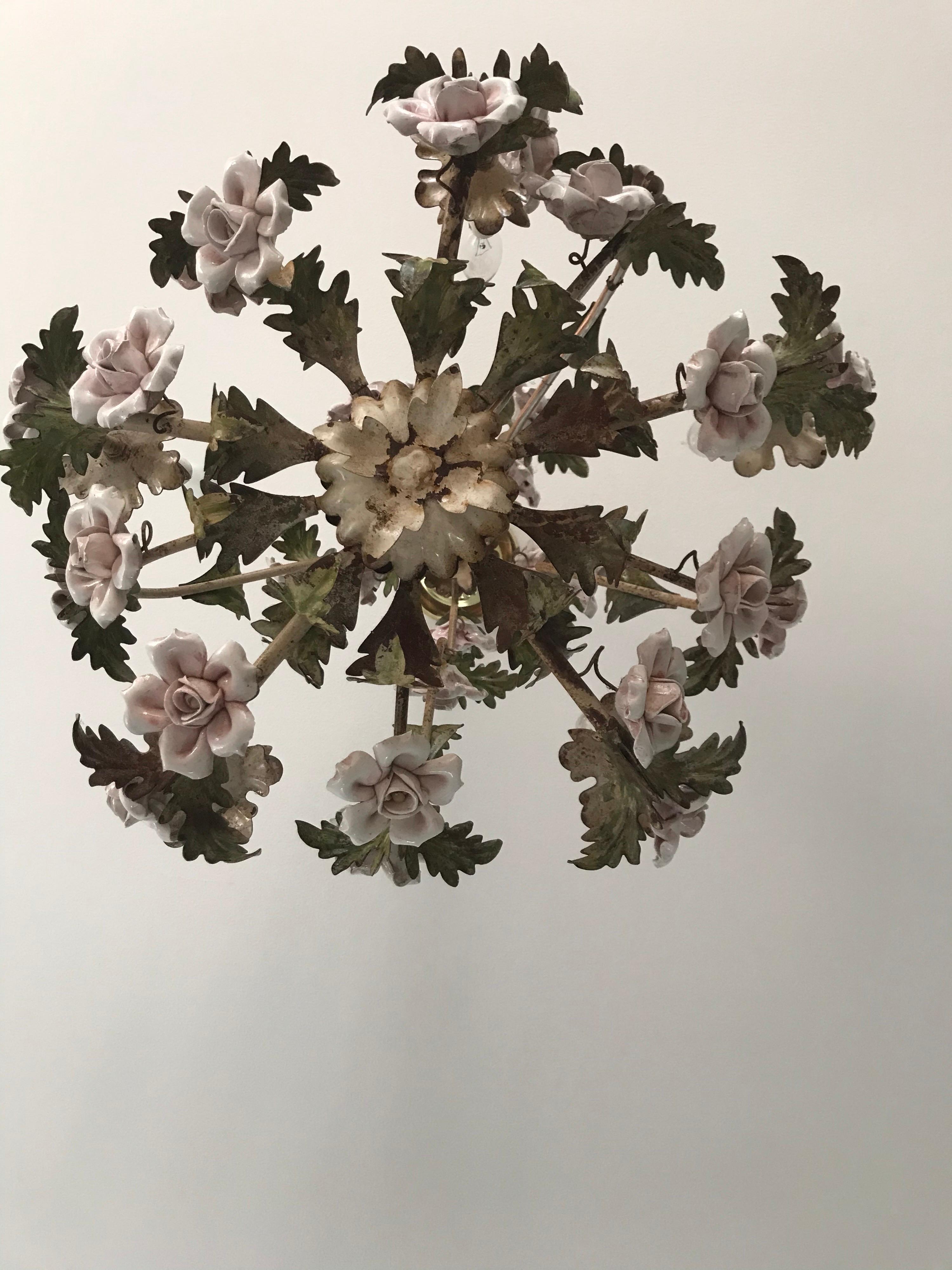 This charming vintage tole chandelier is the iconic feminine lighting fixture to enhance a bedroom, bathroom, or powder room. Made of iron, this chandelier features an abundance of elegant pink painted roses and leaves. Crafted circa 1940s, this