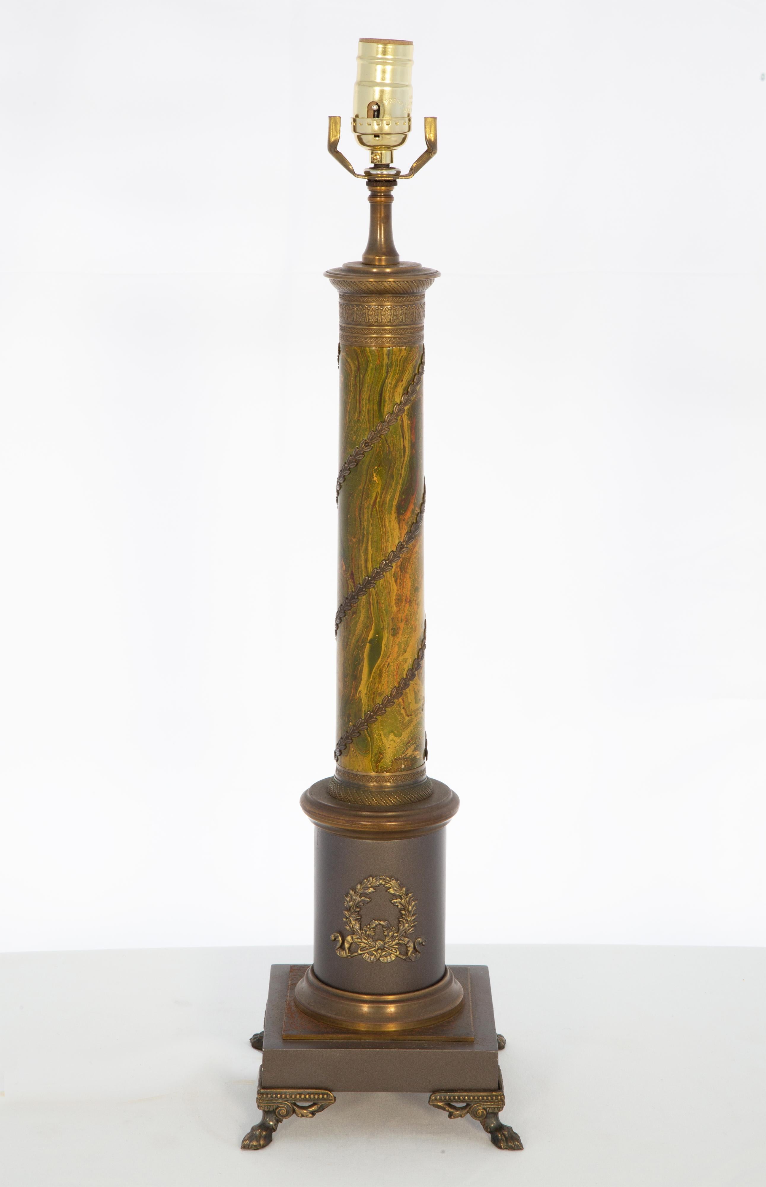 Single tole Empire style columnar lamp, having a round central column with marbelized finish, wrapped in foliate spiral decoration, raised on graduated plinth base, raised on paw feet.

Stock ID: D4040