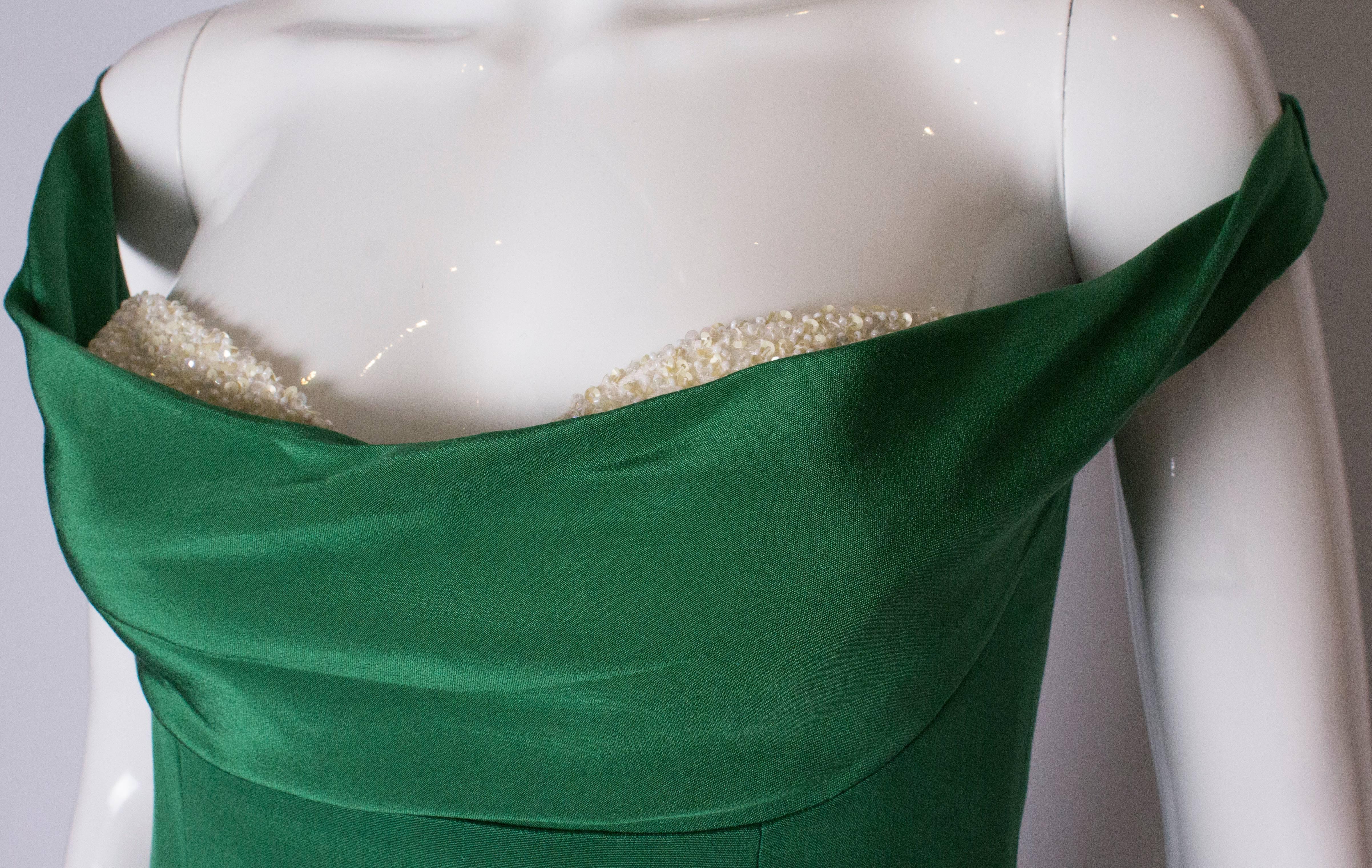 A chic cocktail dress by Tomasz Starzewski. The dress is green with a white beaded front/modesty patch.It is off the shoulder, boned and fully lined with a central back zip. A real head turner.