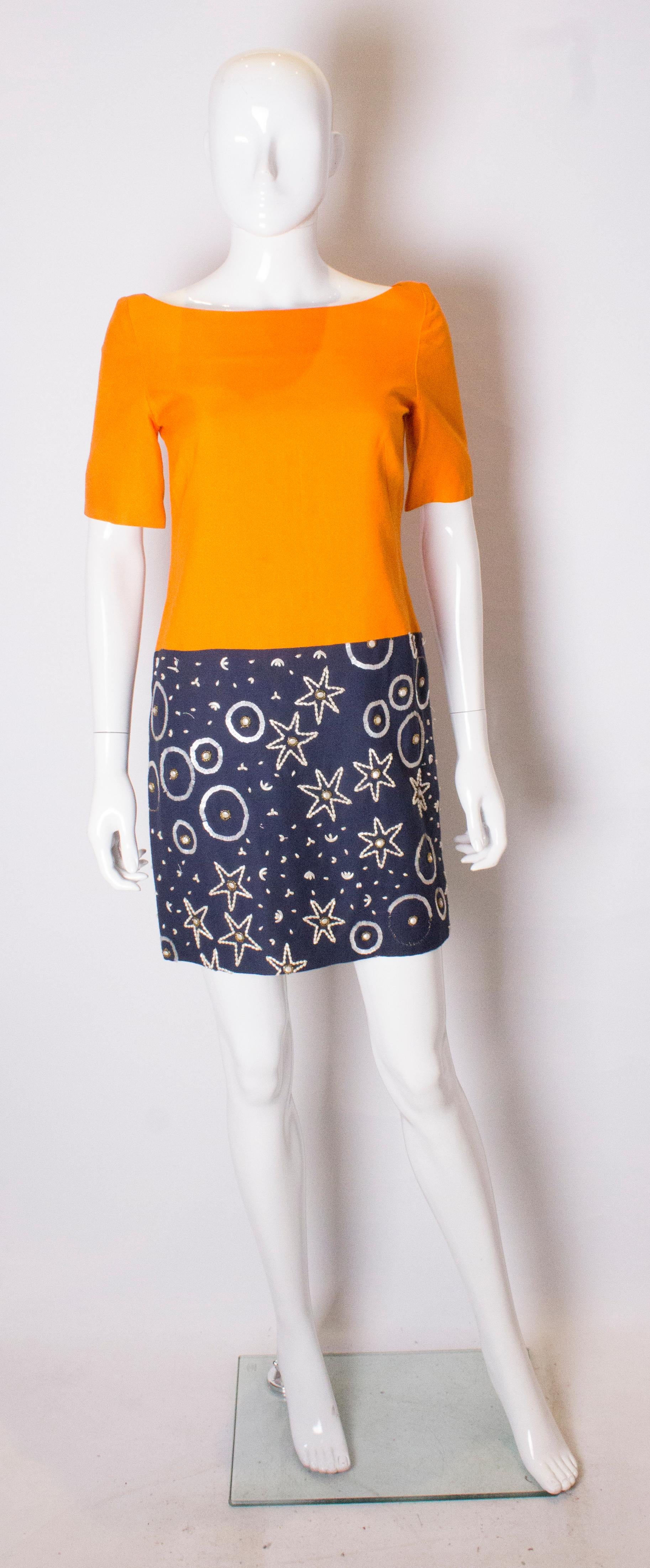 A chic cocktail dress by Tomasz Starzewski in a colourful raw silk. The upper part is in this seasons orange colour and the lower skirt is blue with bead detail. The dress is fully lined and has a central back zip.