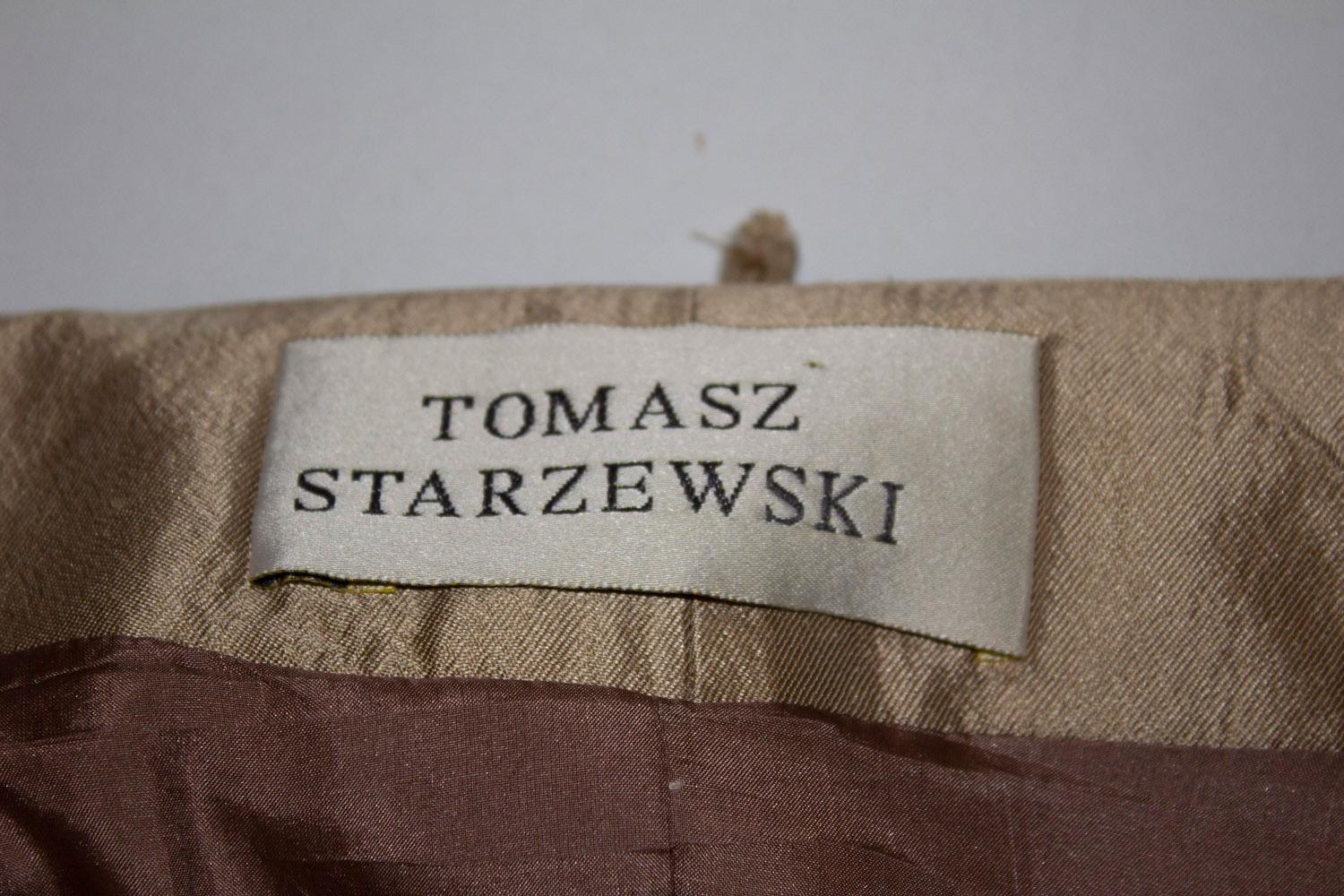 A stunning vintage jacket by Tomasz Starzewski. In a soft gold fabric, the jacket has a v neckline, self fabric wide belt  and great tailoring . It is fully lined.  Measurements: Bust  up to 36'', length 22''
