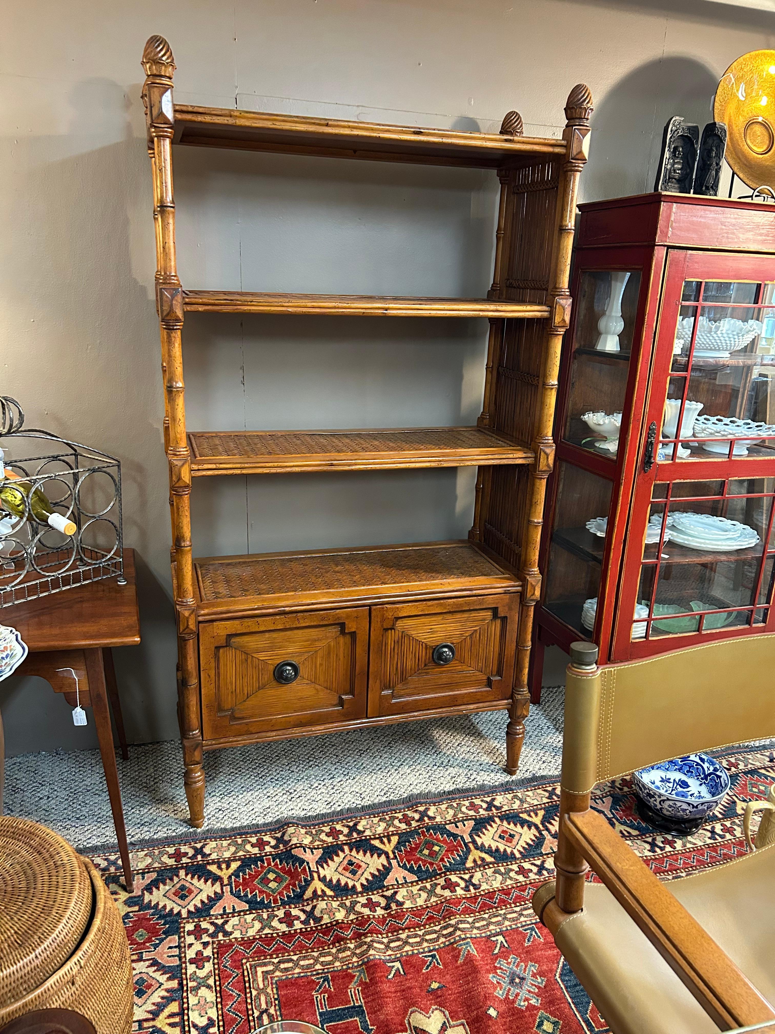 Bellissima libreria in bambù e rattan intrecciato color miele con una struttura in legno pesante e sostanziale, con 4 ripiani e due cassetti per le cartelle nella parte inferiore. Gli splendidi finials nella parte superiore e i piedi torniti sono