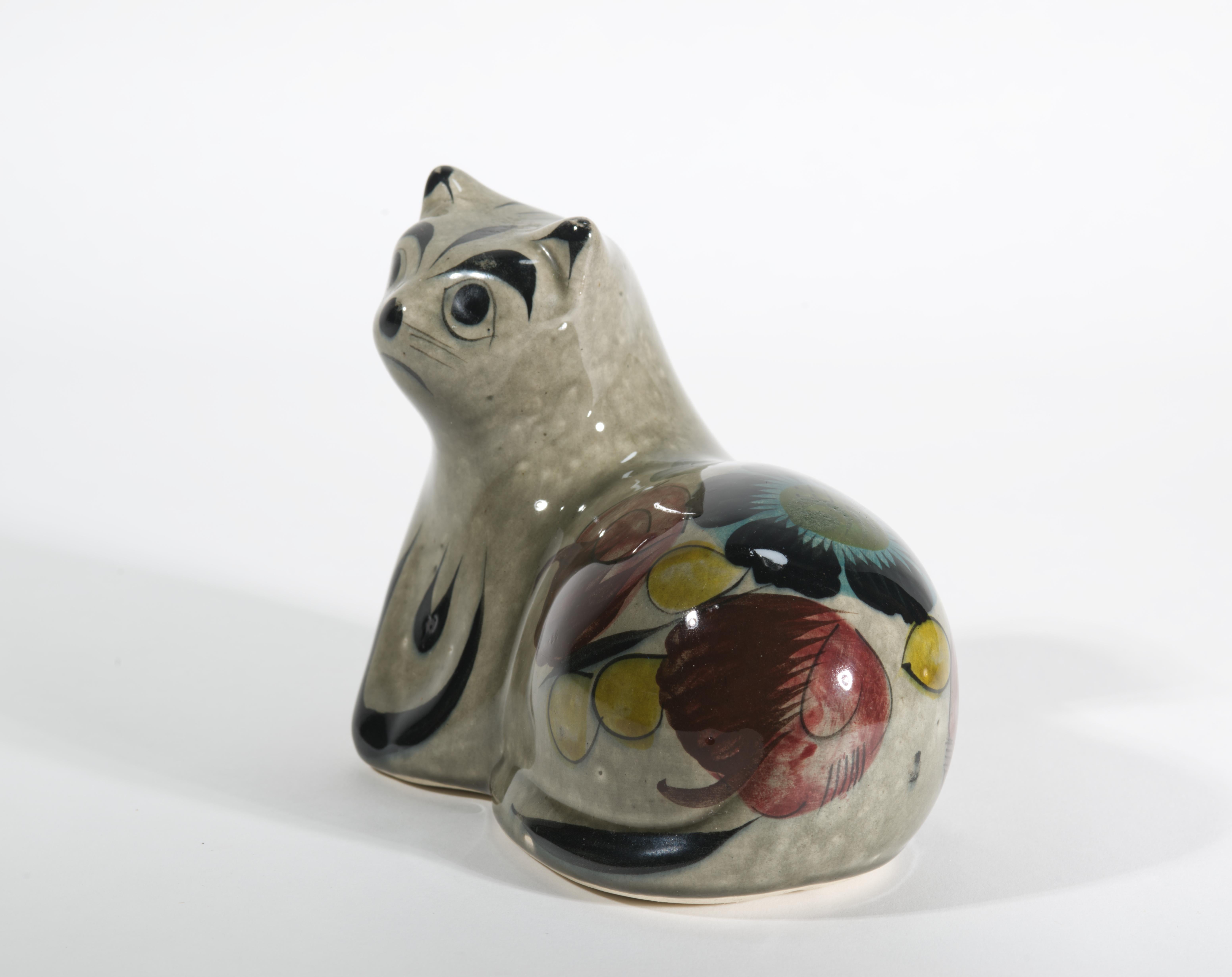  Charming vintage Tonala pottery figurine depicts a reclining cat with folded front paws and raised head; the cat is looking forward with wide open, large eyes and a slightly surprised look on its face. The cat body is decorated with beautiful hand