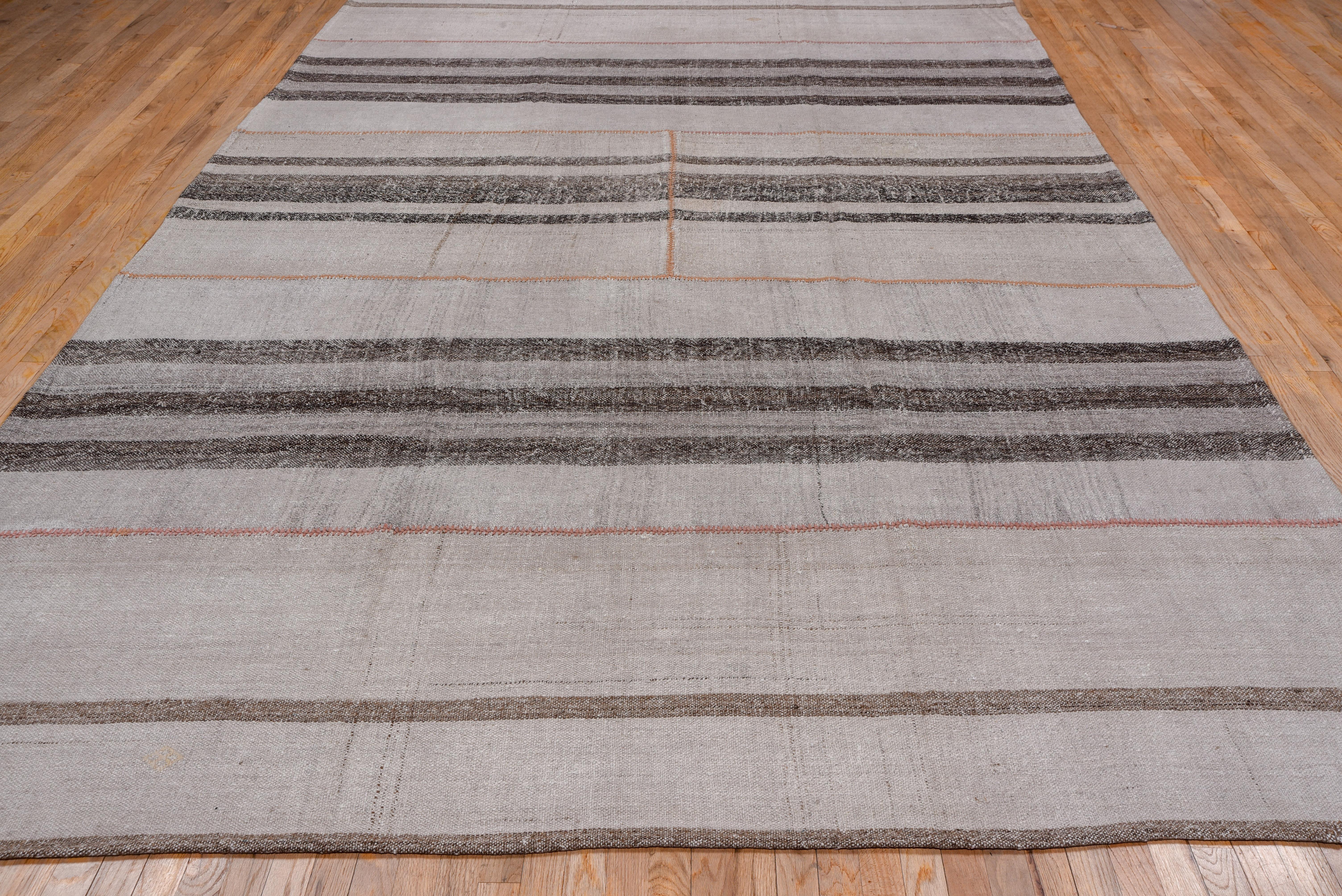 Constructed of six parts in five horizontal bands, with warp-faced wool panels striped beige and brown The sections were parts of long bands which were then cut up and joined to make this rustic weaving.