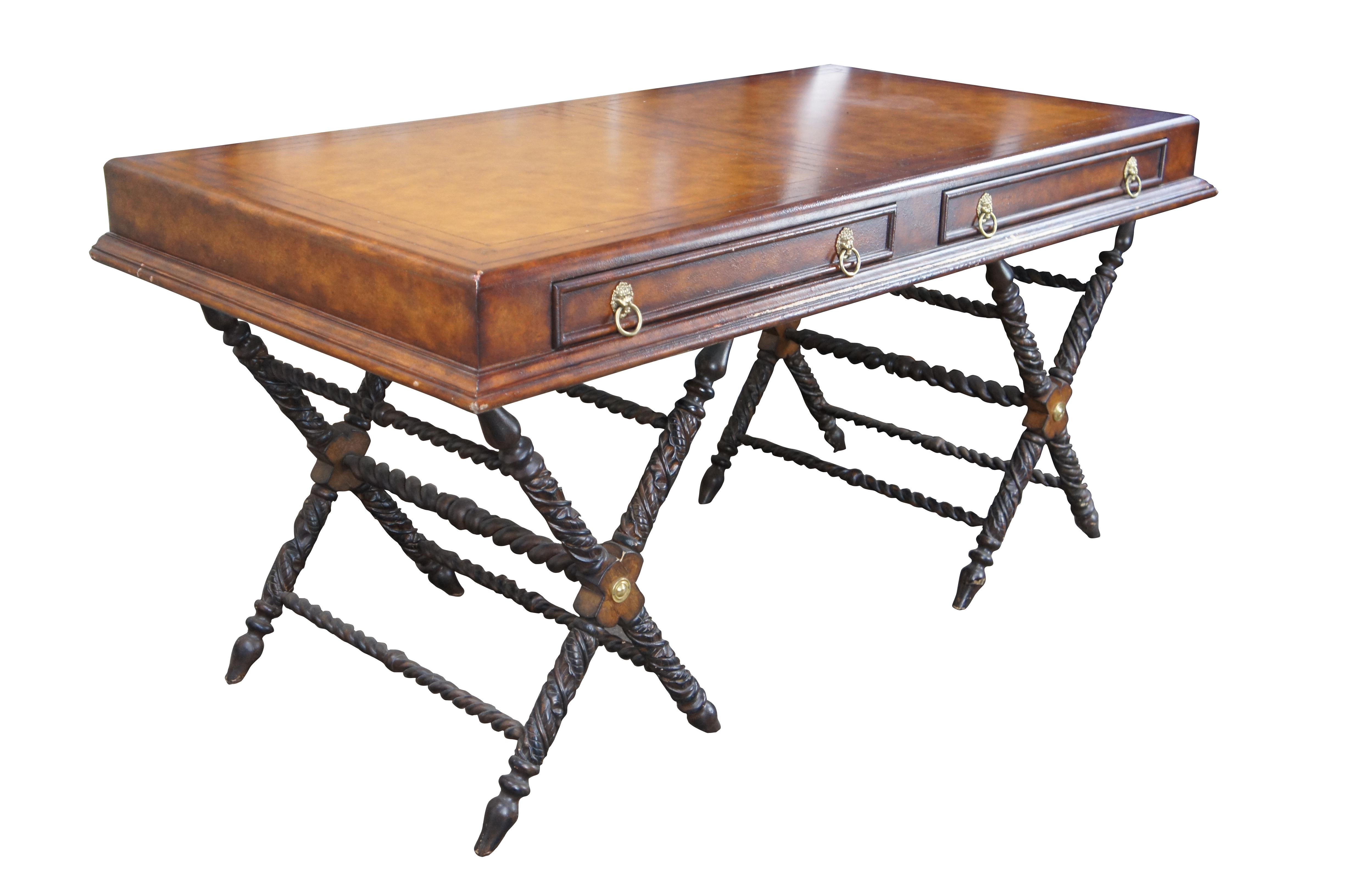 Late 20th Century campaign style desk. Features a rectangular form with brown tooled leather top and two drawers in the frieze. Each drawer has brass lion knocker pulls. The desk is supported by carved and twisted X form pedestal base. Made in the