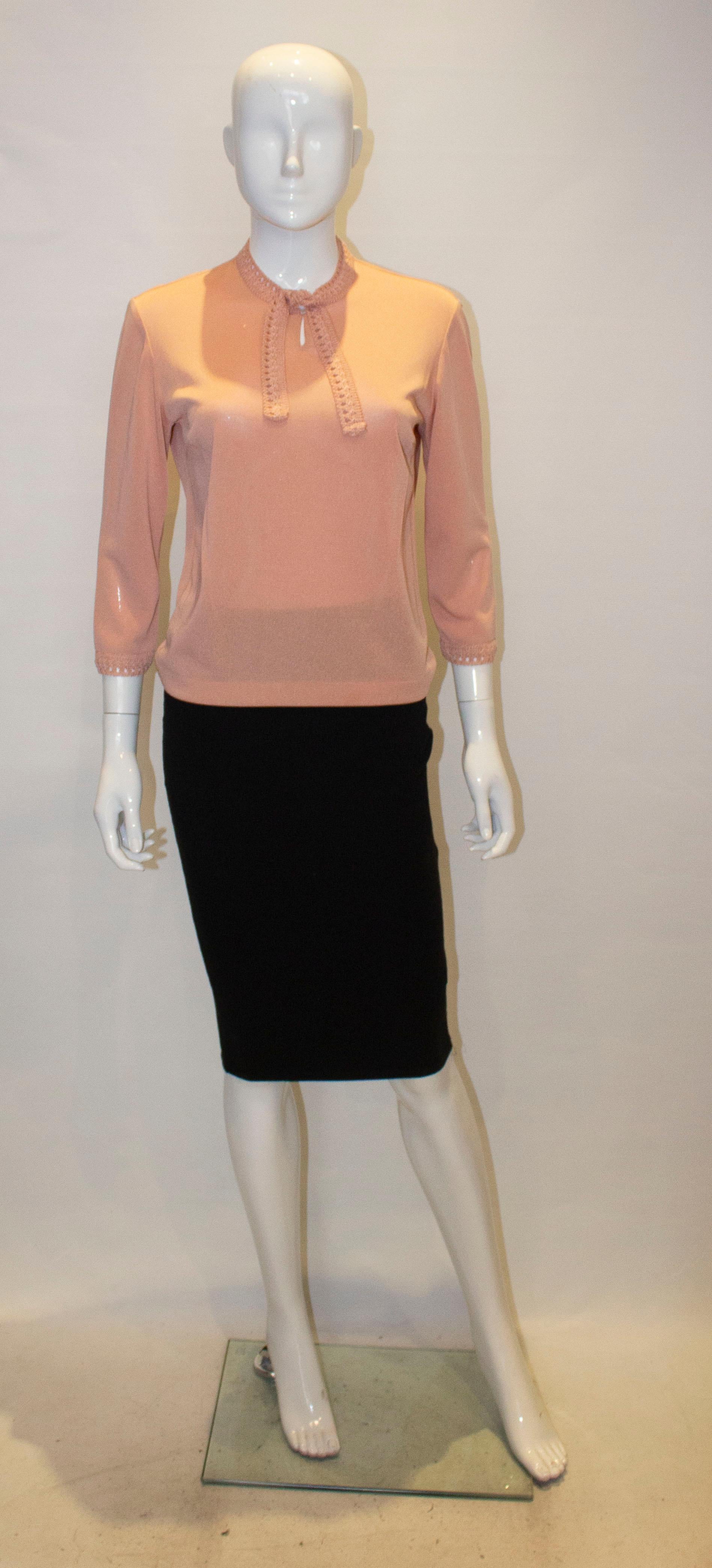 A pretty vintage knit for Spring by Creation Anne Laroye.In a pretty pink colour the top has decoration at the neck and the cuffs, with a tie at the neck and a single button opening. 