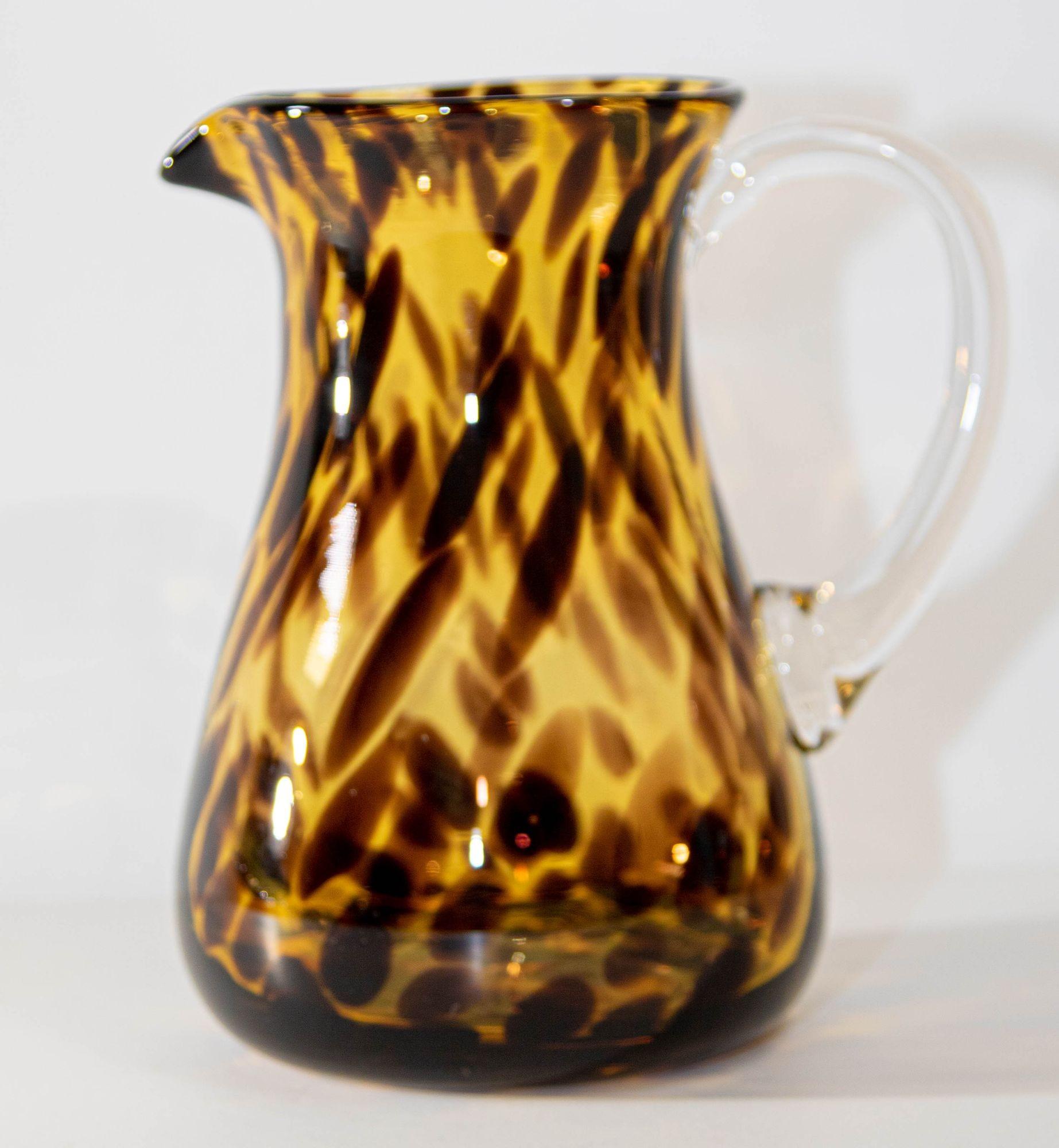 Vintage hand-blown glass pitcher in a tortoise shell pattern.
Elegant barware hand blown tortoise shell glass pitcher amber with clear glass handle.
A distinctive tortoise shell motif brings rich color and dimension to a glass carafe that makes a
