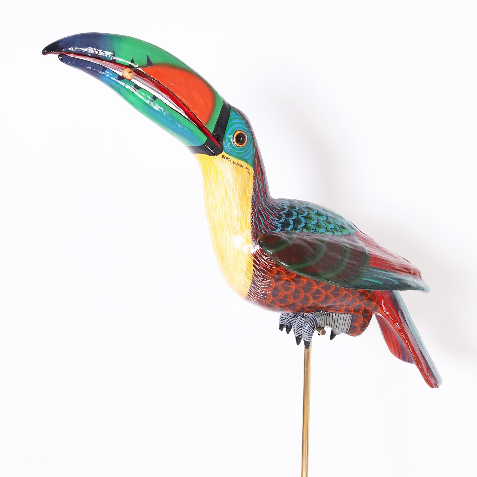 Whimsical mid century toucan sculpture handcrafted in paper mache and decorated in bold tropical colors signed Sergio Bustamante, numbered 25/100 and presented on a brass stand.